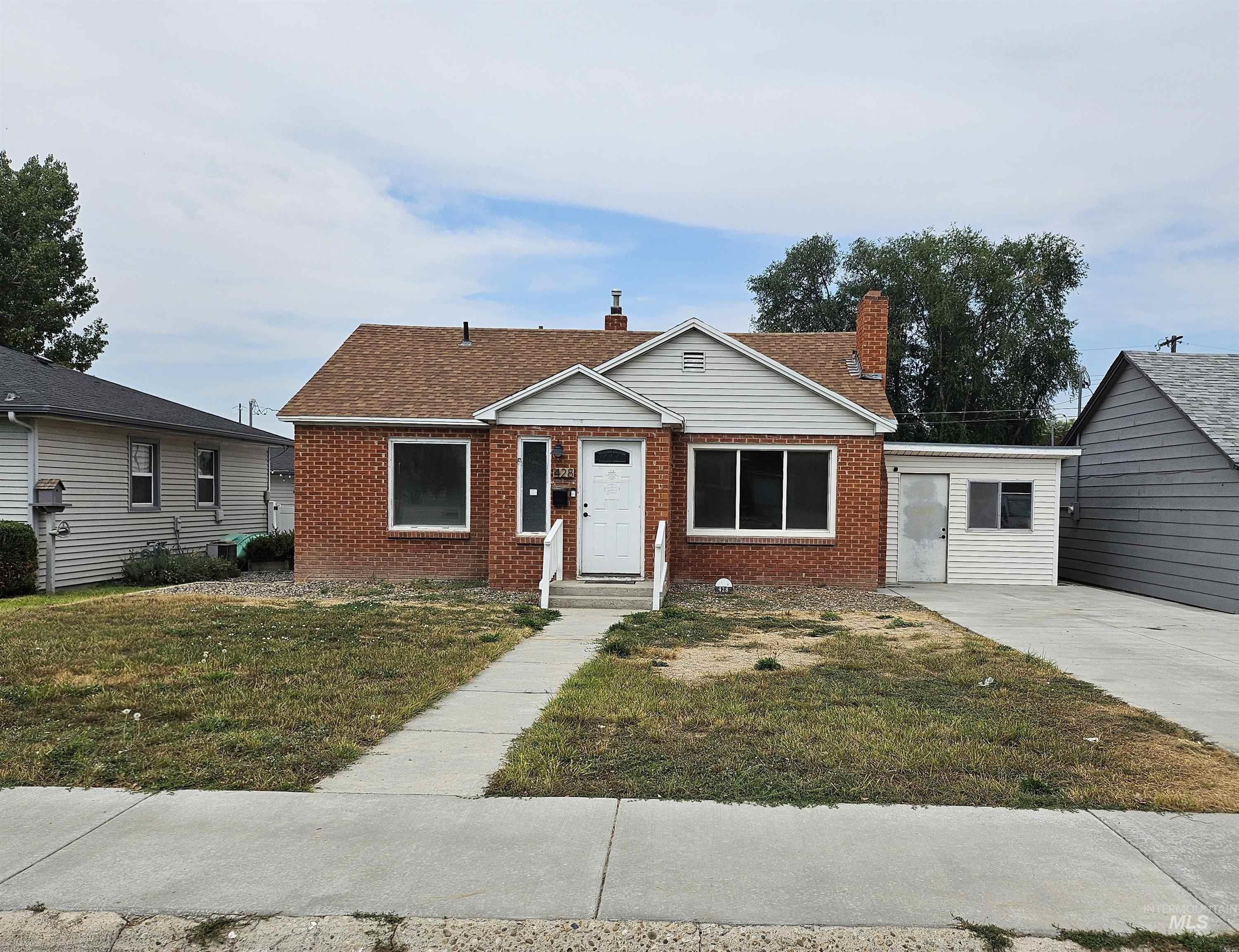 Bungalow-style house with a chimney, a front lawn, brick siding, and a shingled roof