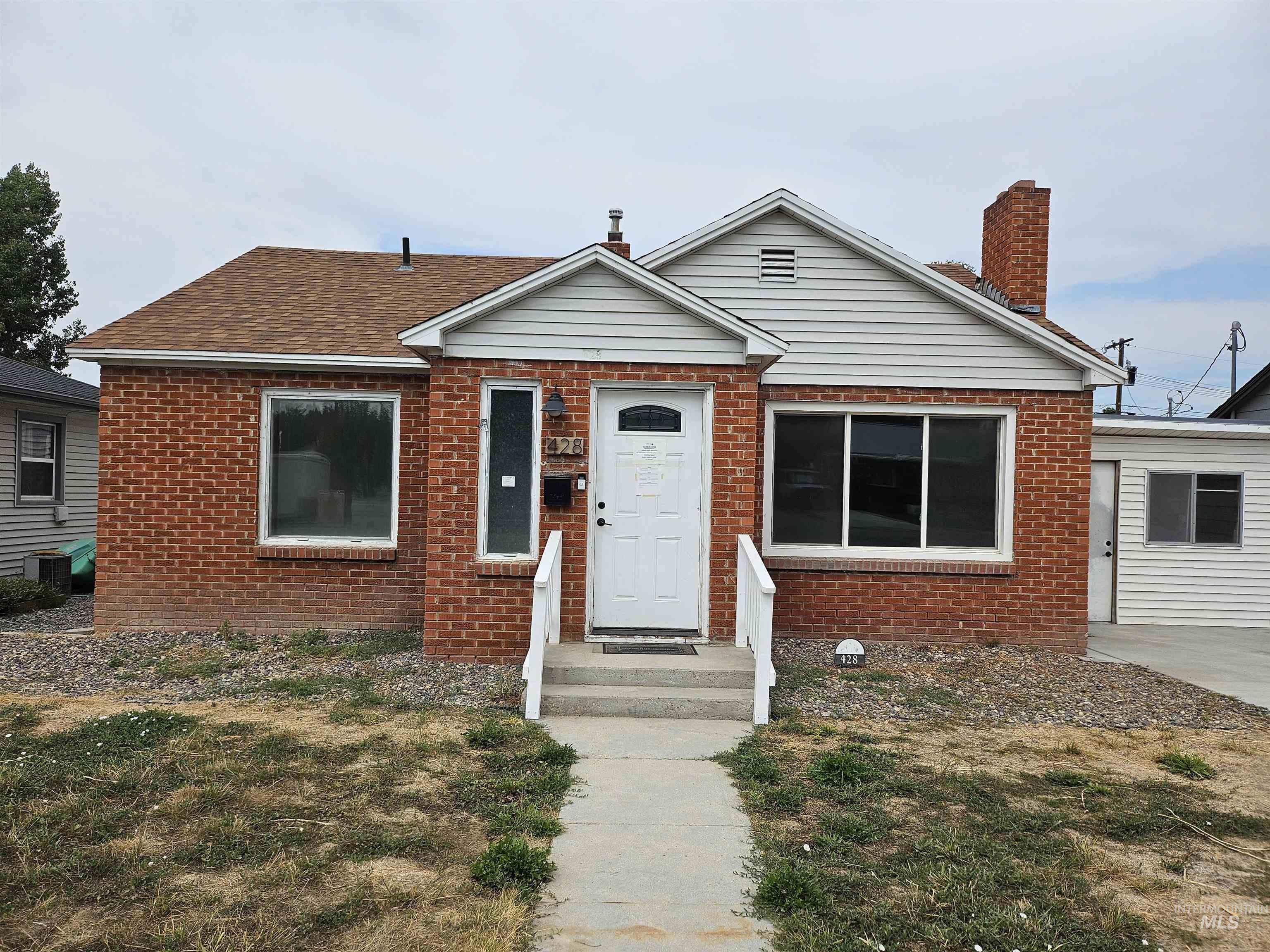 Bungalow-style house featuring brick siding and a chimney