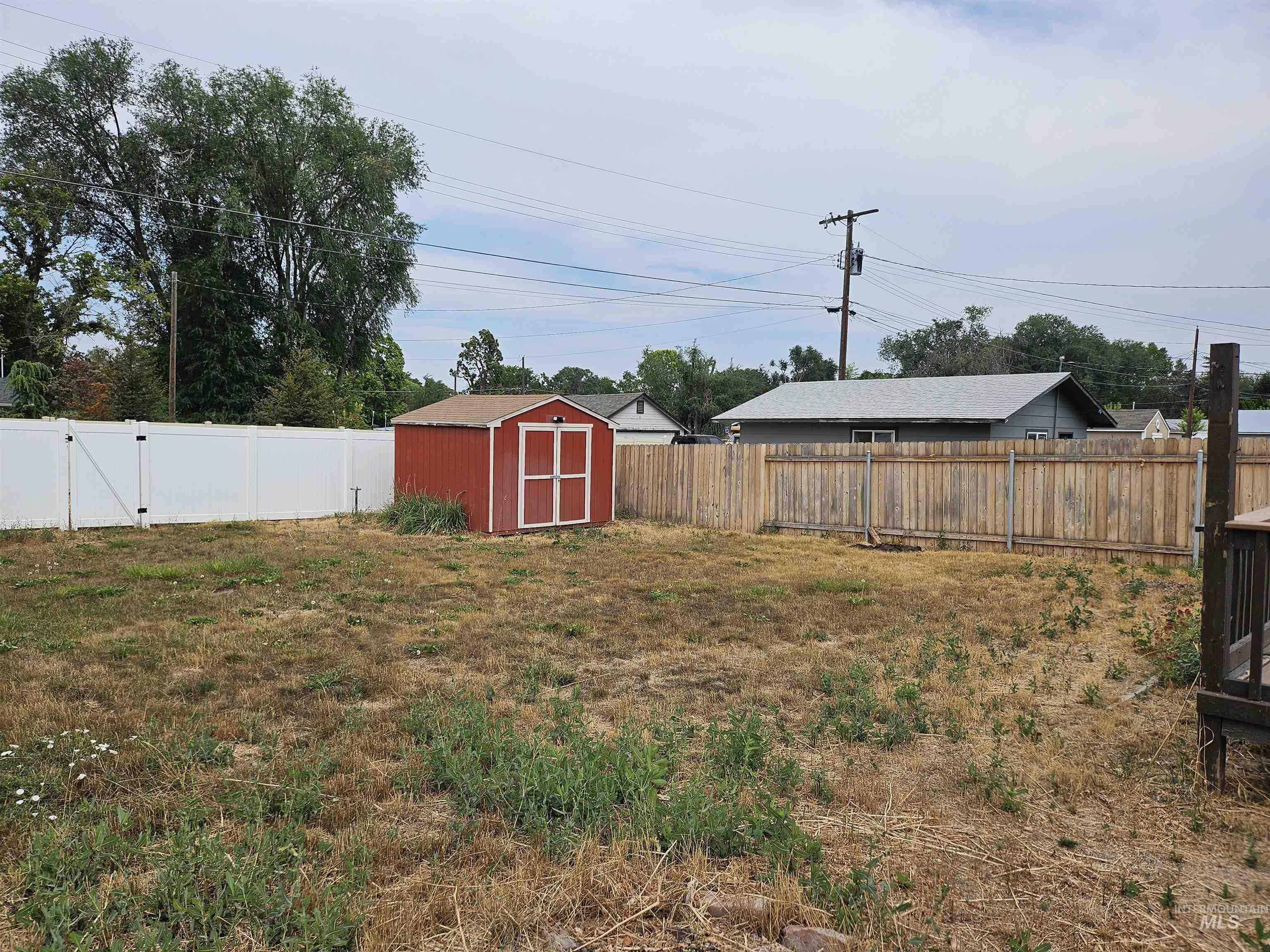 Fenced backyard featuring a storage shed