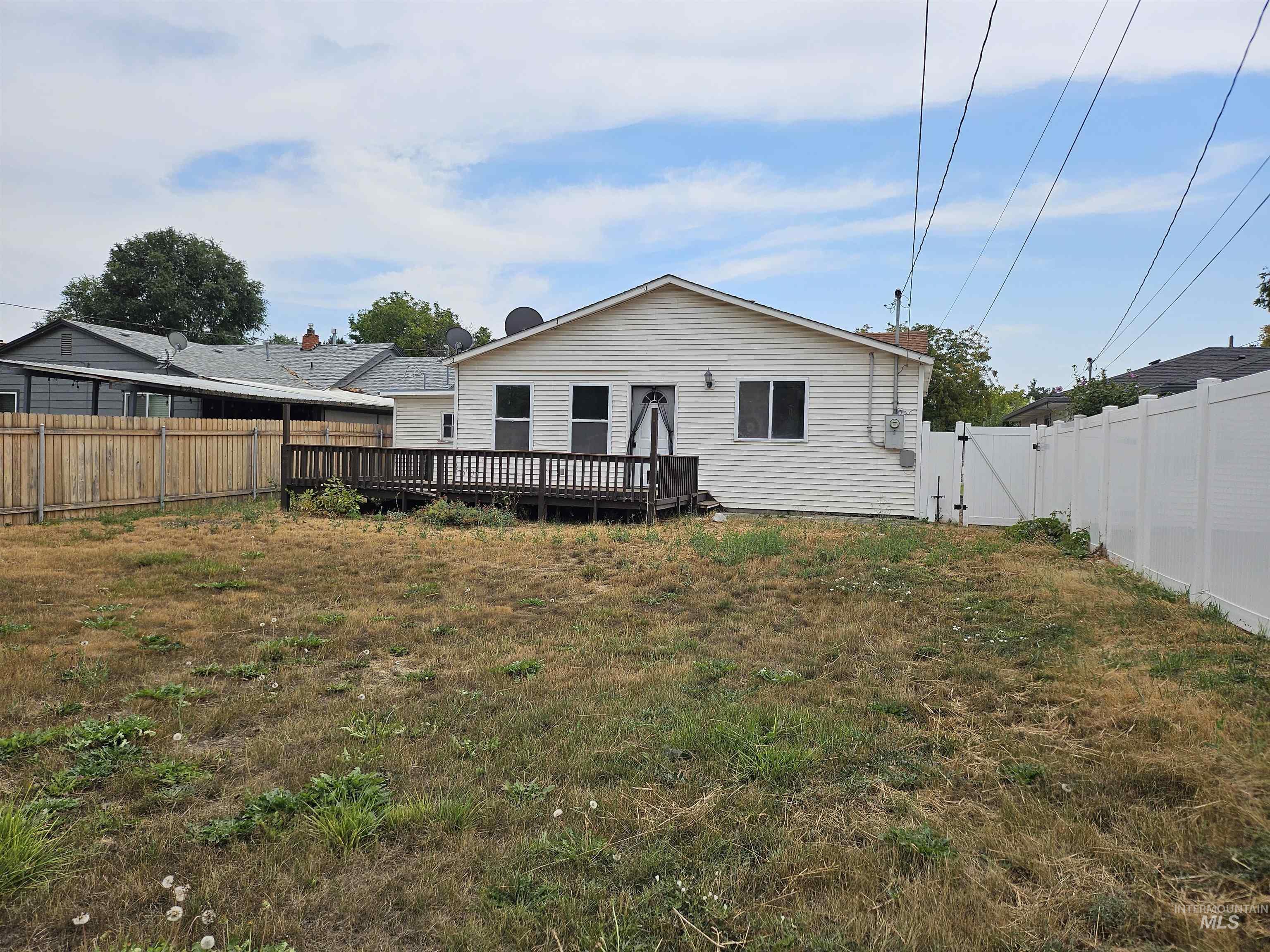Back of property with a fenced backyard, a wooden deck, and a gate