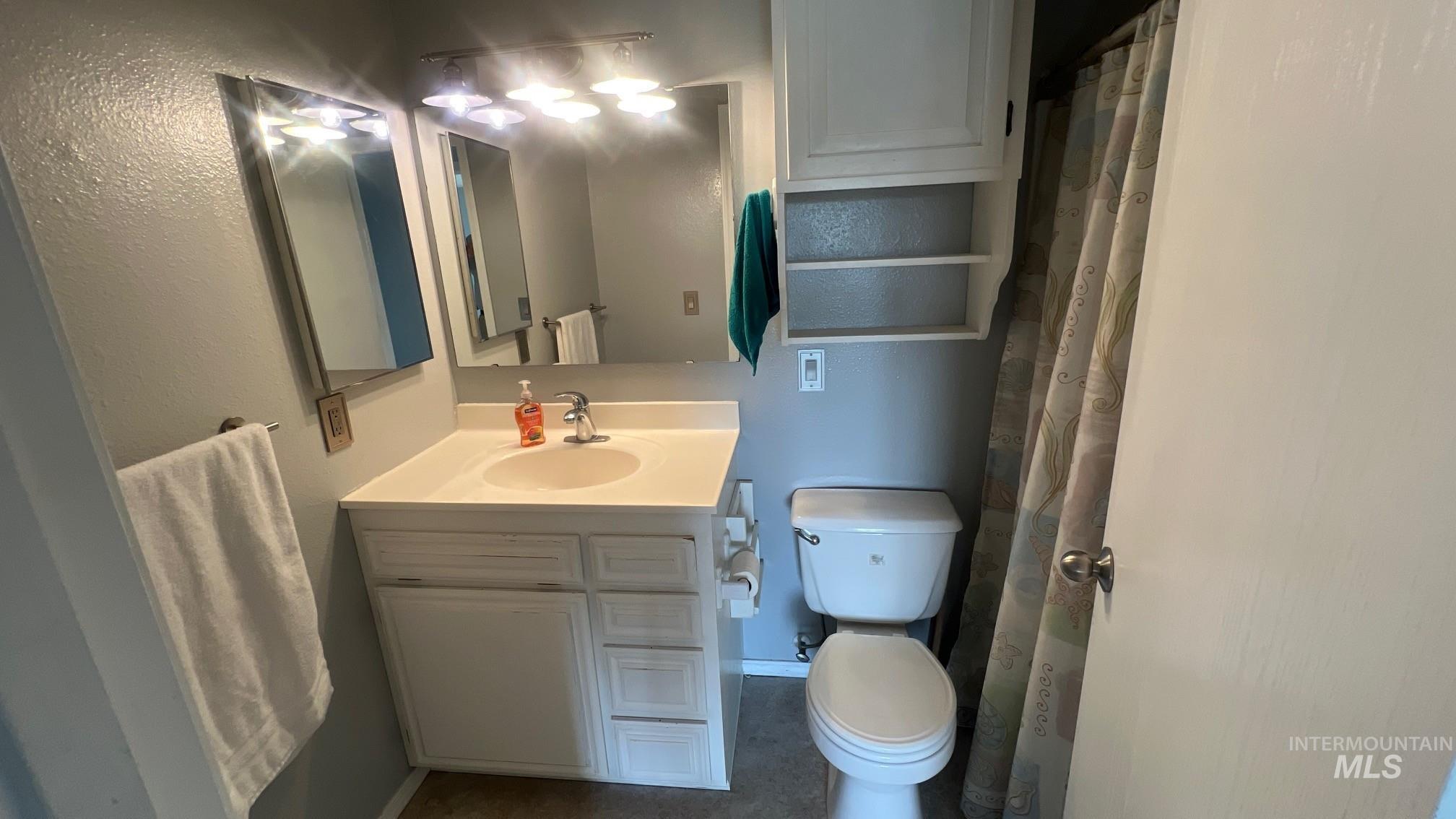 Bathroom with vanity, a shower with shower curtain, and a textured wall