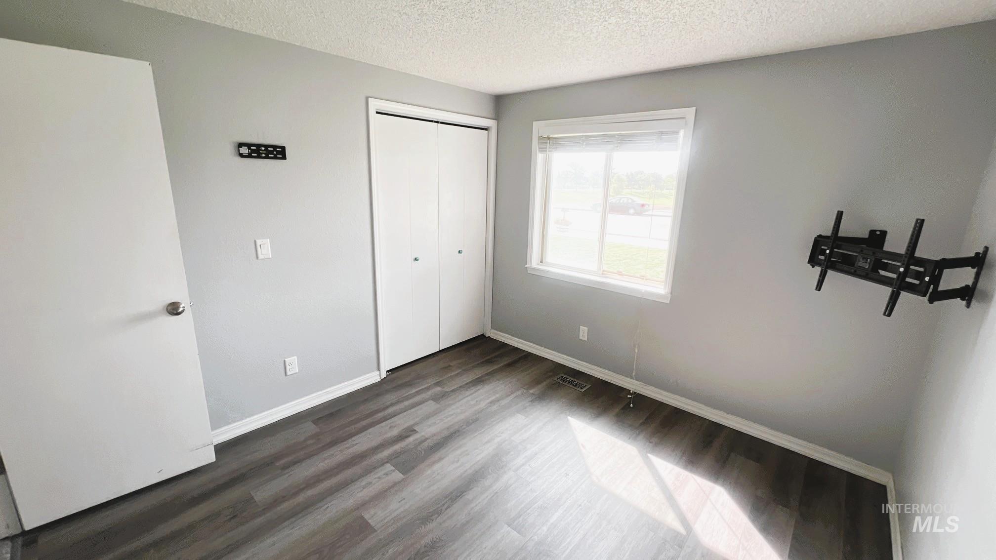 Unfurnished bedroom with wood finished floors, a textured ceiling, and a closet