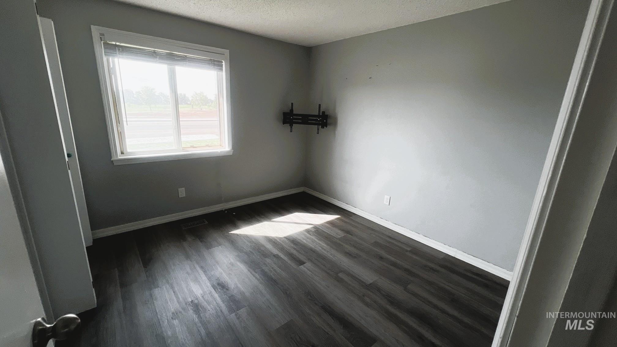 Unfurnished bedroom featuring dark wood finished floors and a textured ceiling