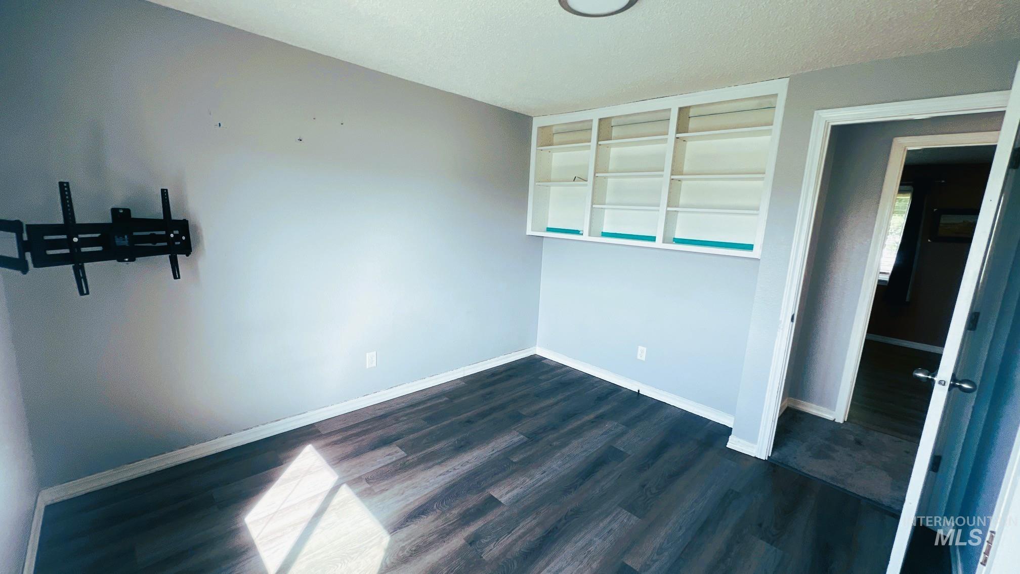 Unfurnished room with dark wood-type flooring and a textured ceiling