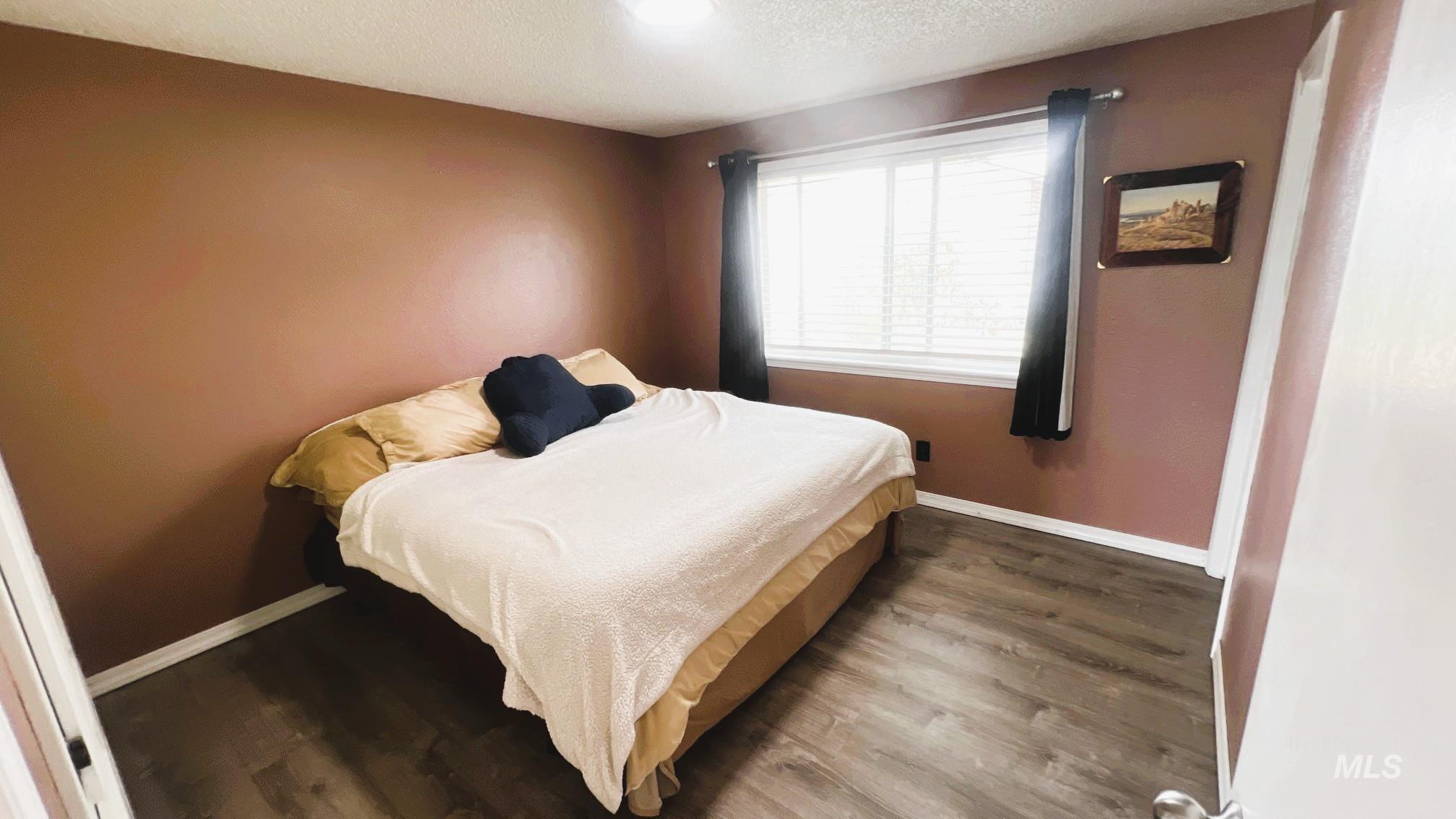 Bedroom with wood finished floors and a textured ceiling