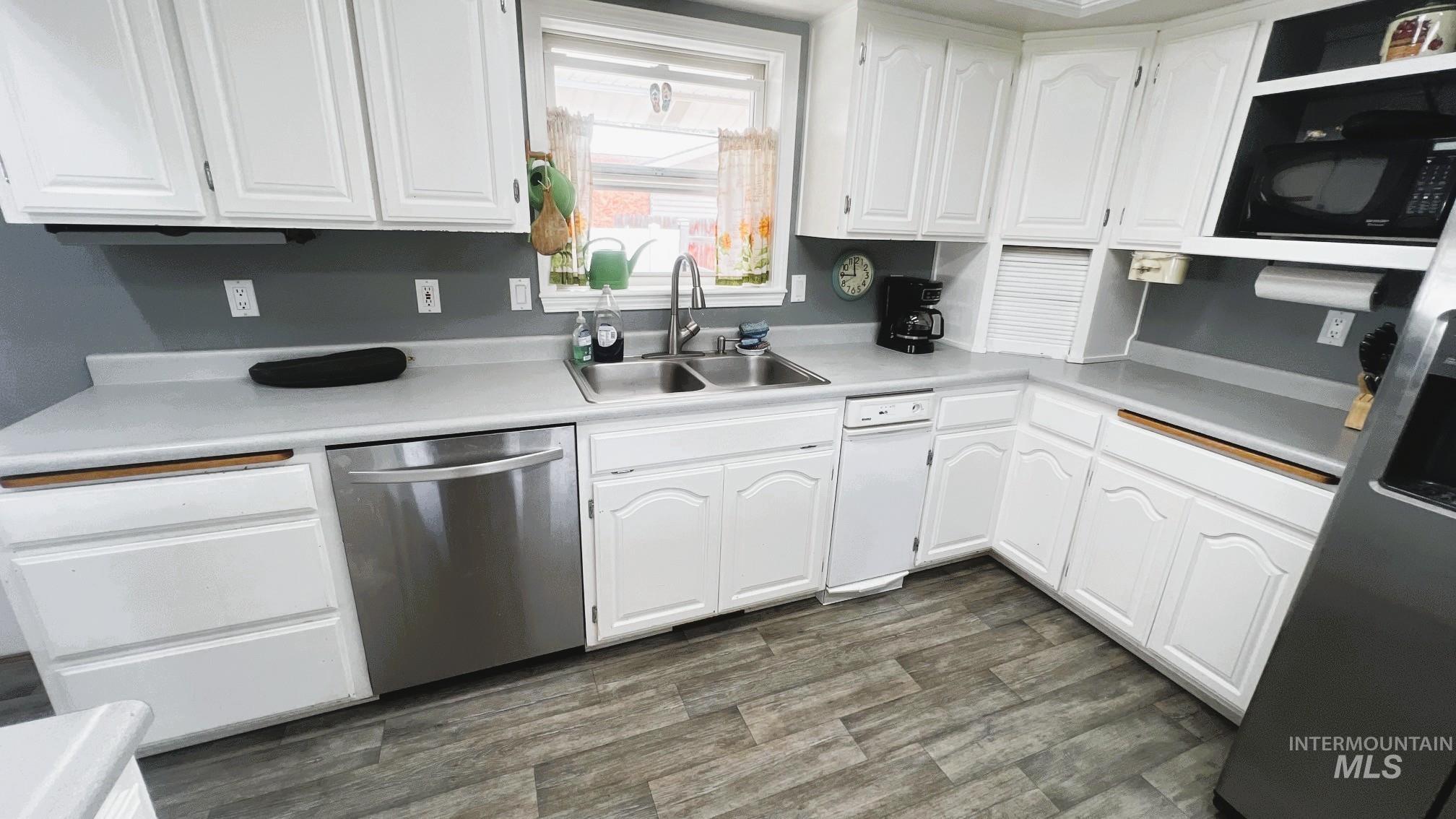 Kitchen featuring white cabinetry, dishwasher, light countertops, dark wood finished floors, and black microwave