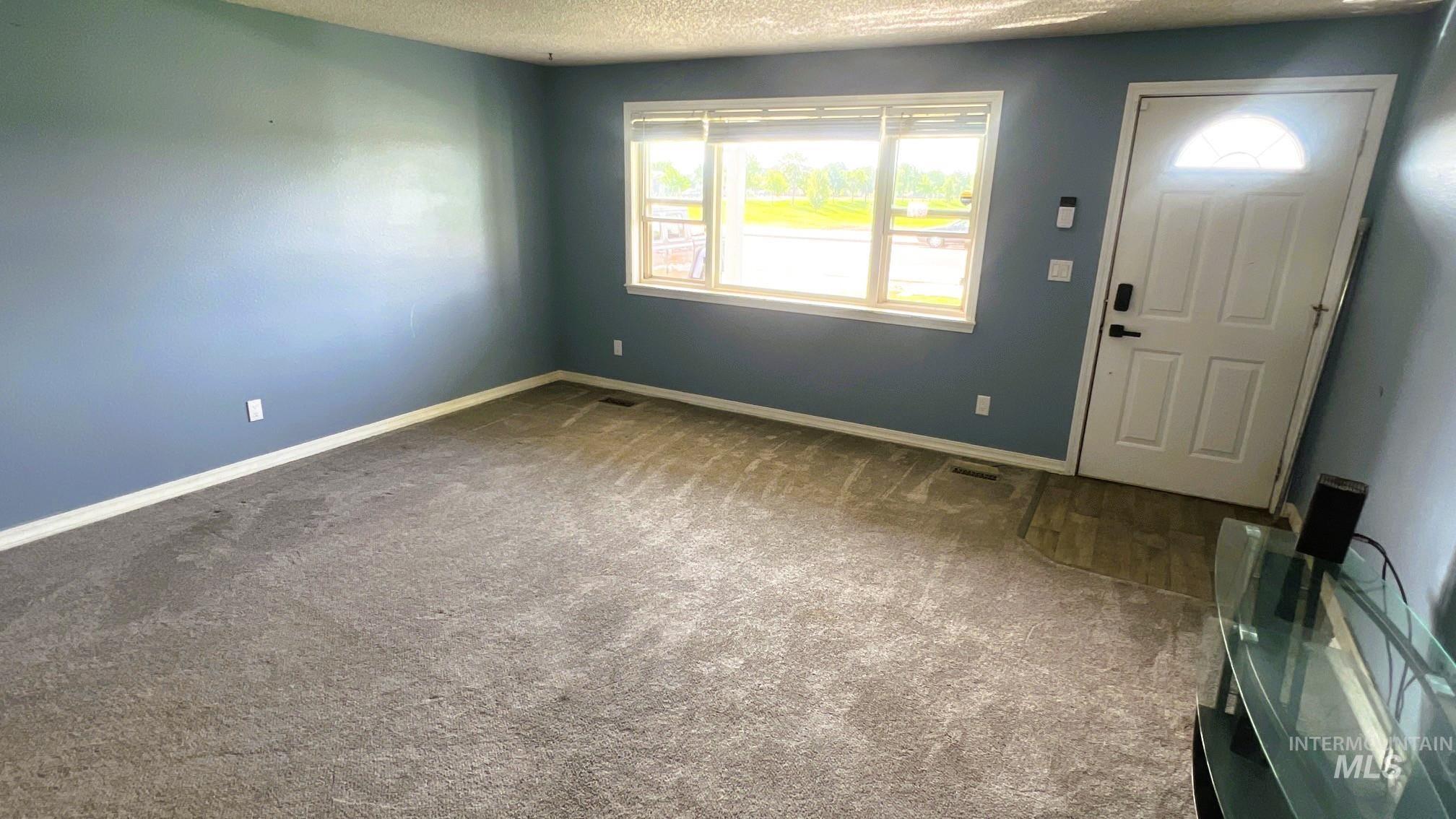 Carpeted entrance foyer with a textured ceiling and baseboards
