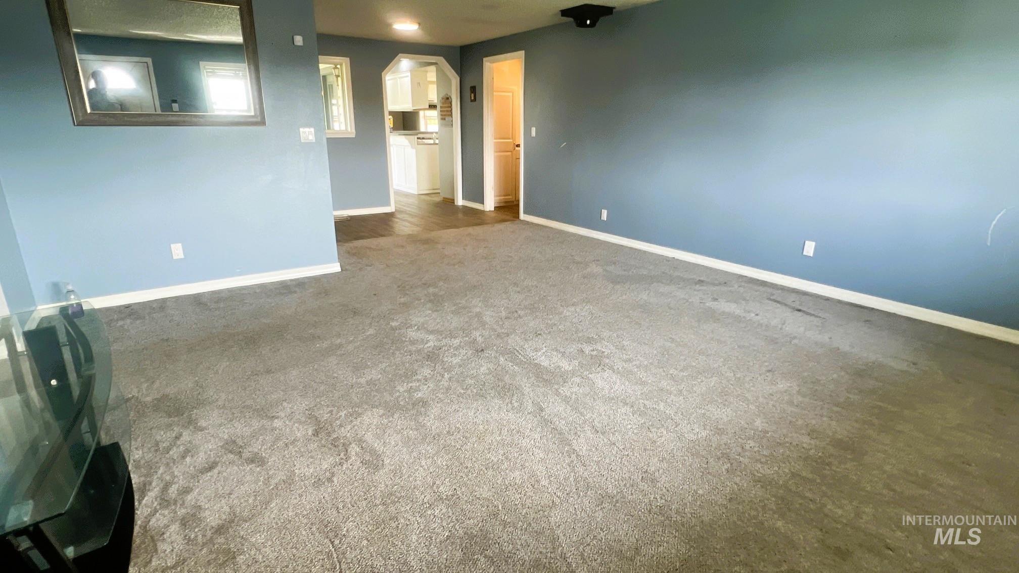 Unfurnished room featuring dark carpet and baseboards
