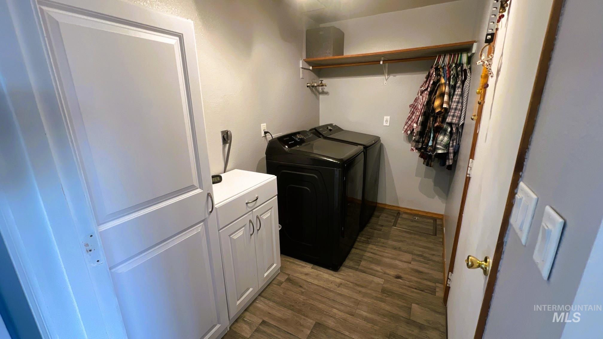 Laundry area with dark wood-style floors, cabinet space, and washer and dryer