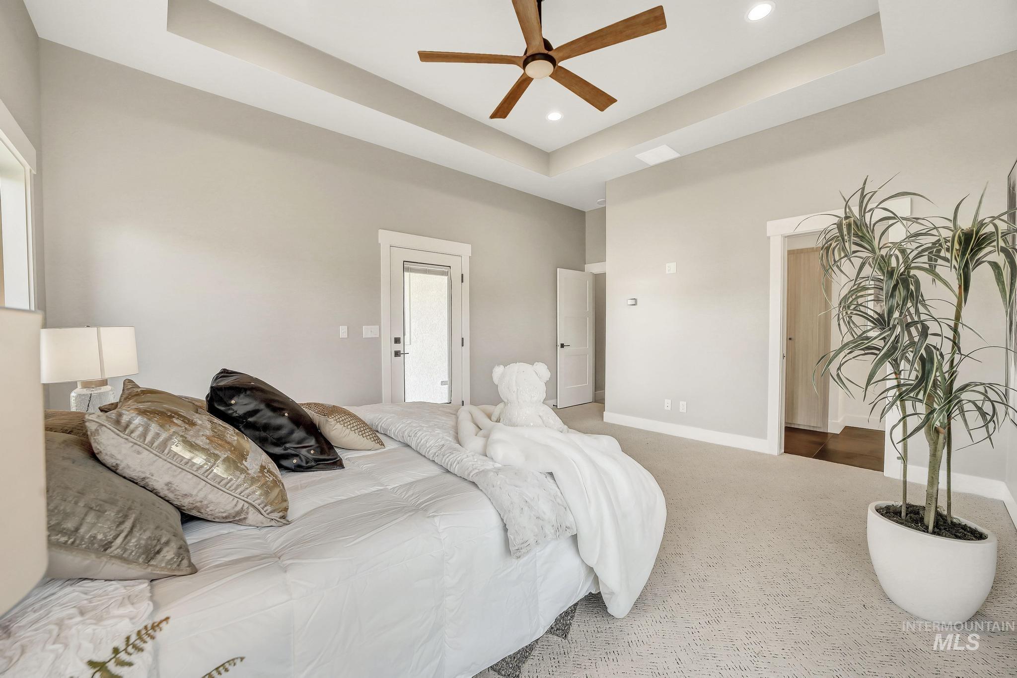 Bedroom with a raised ceiling, carpet floors, and ceiling fan