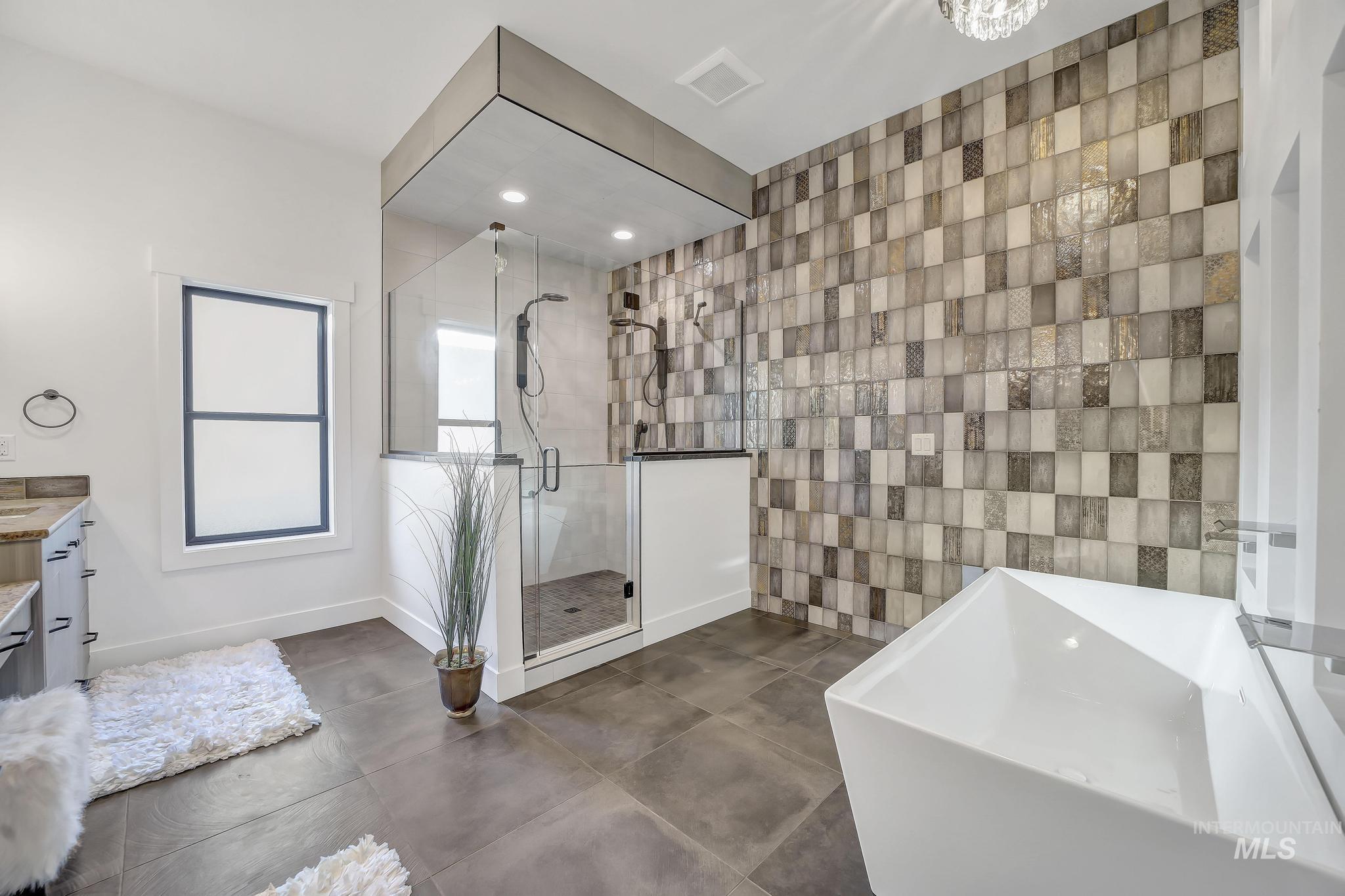 Bathroom with a freestanding tub, a shower stall, vanity, tile walls, and recessed lighting