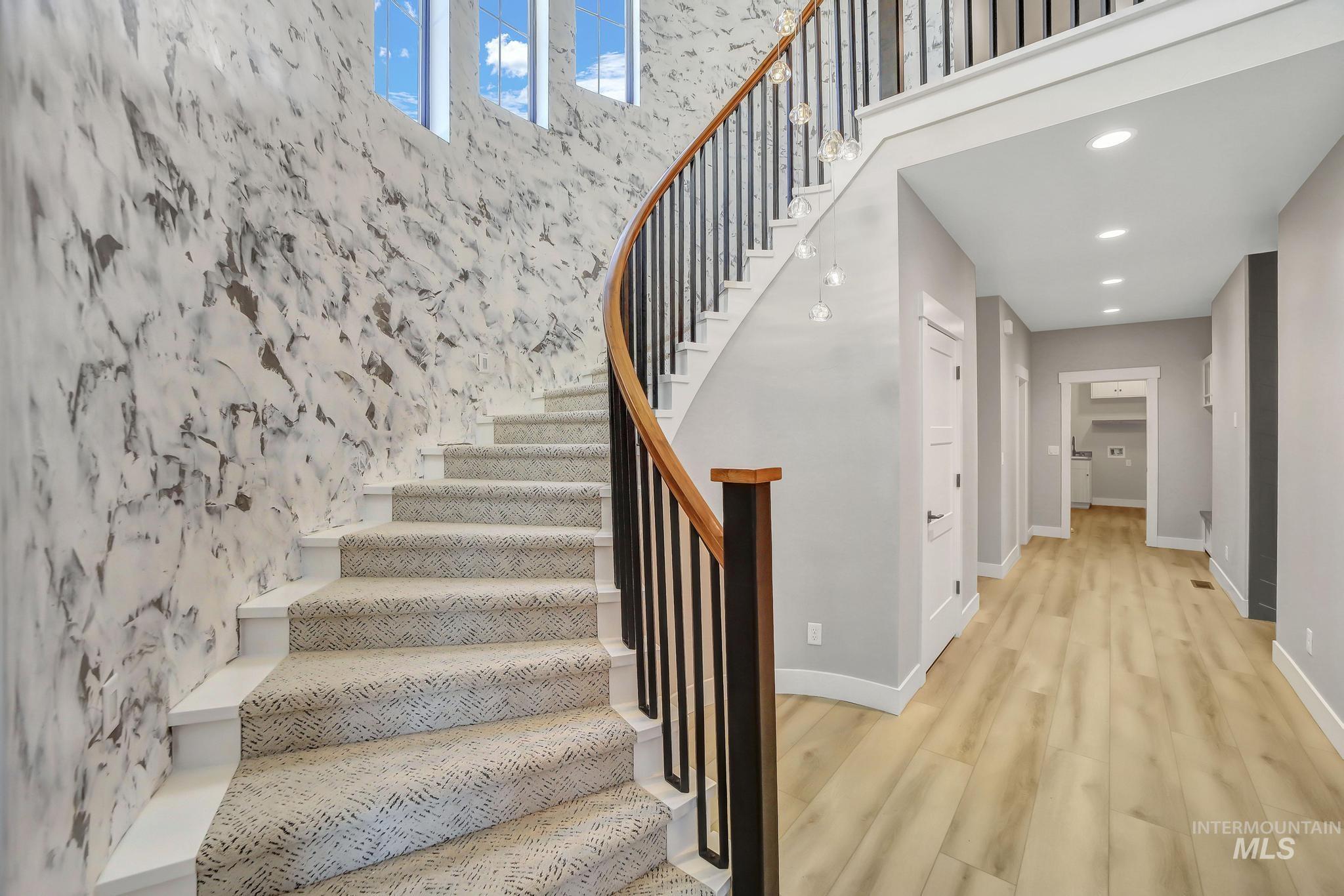 Stairs with wood finished floors, recessed lighting, and a high ceiling