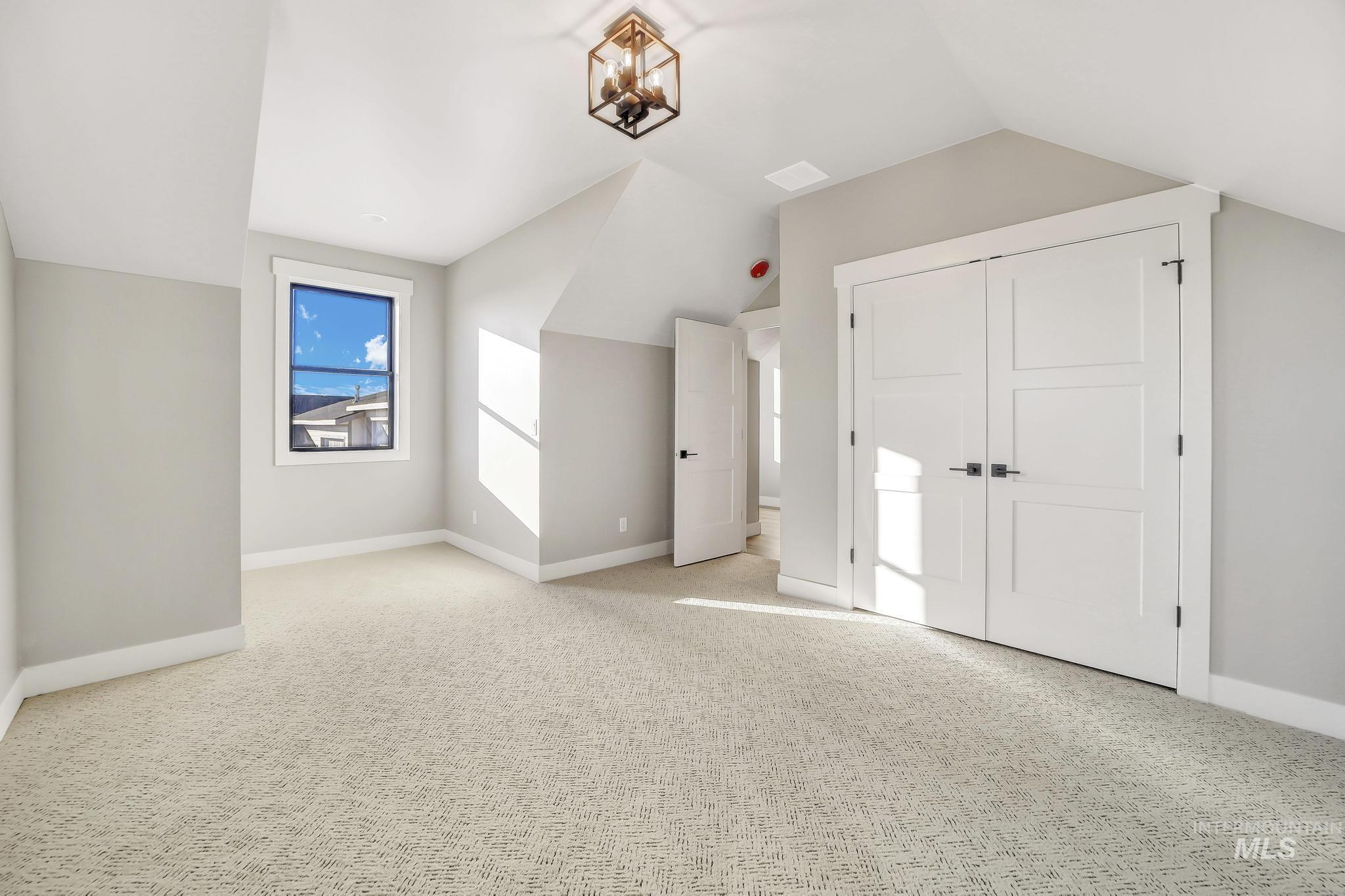 Additional living space with light colored carpet and lofted ceiling