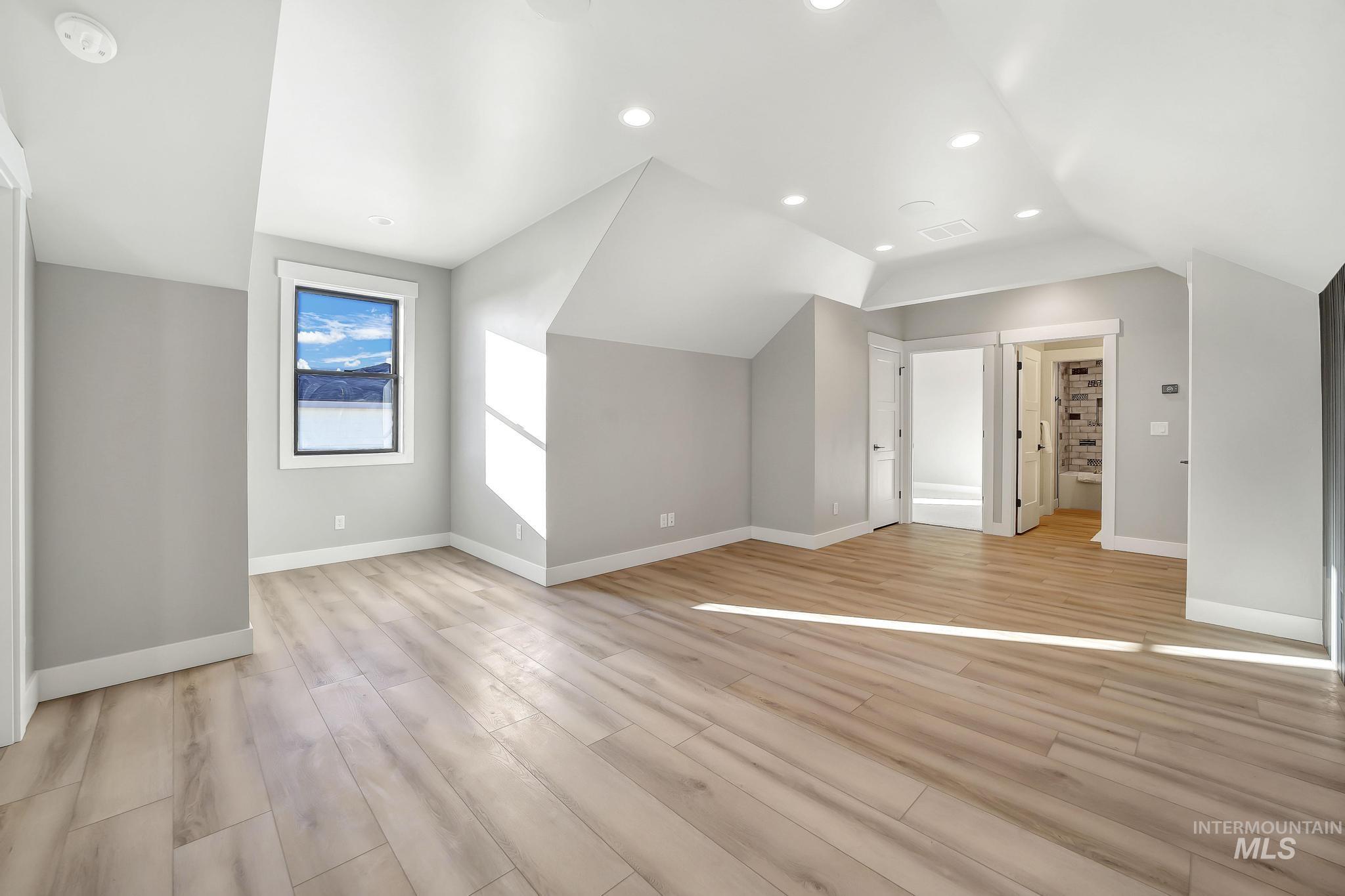 Additional living space with light wood-style floors, vaulted ceiling, and recessed lighting