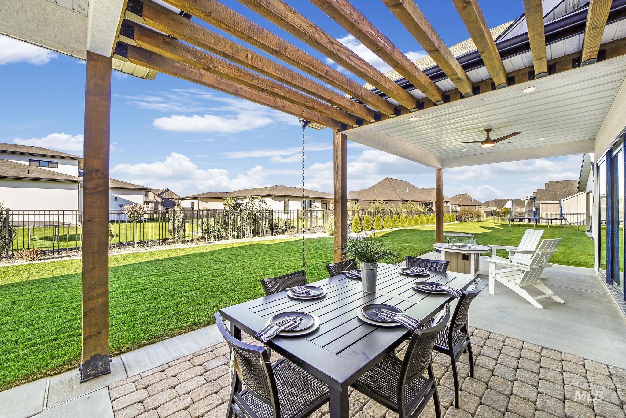 Fenced backyard with a residential view, a pergola, outdoor dining space, and a patio