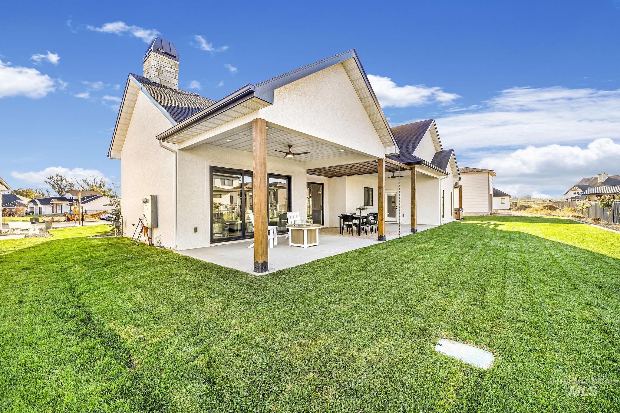 Back of house featuring ceiling fan, stucco siding, a patio area, a yard, and a chimney