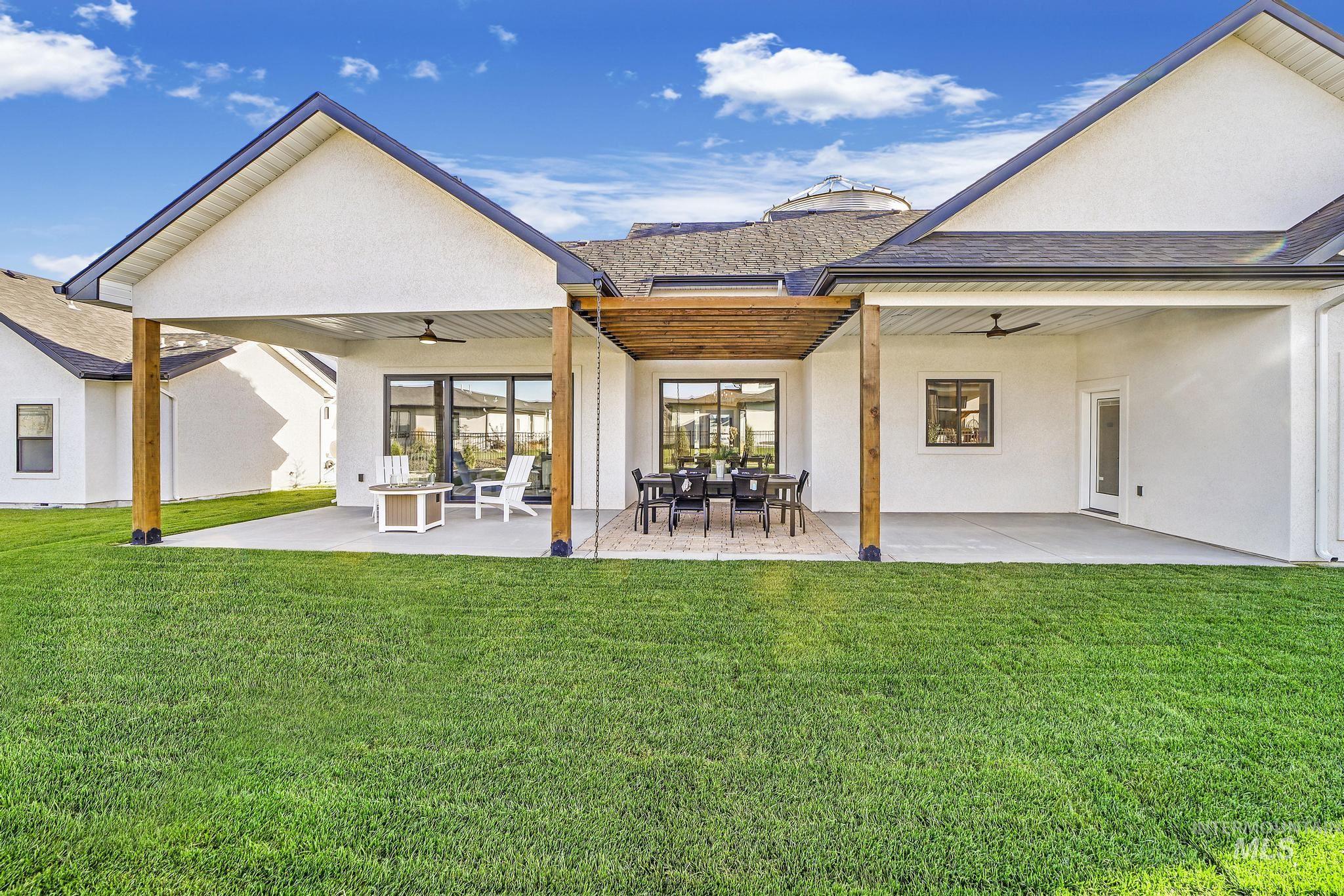 Rear view of house with ceiling fan, a patio, stucco siding, and a yard