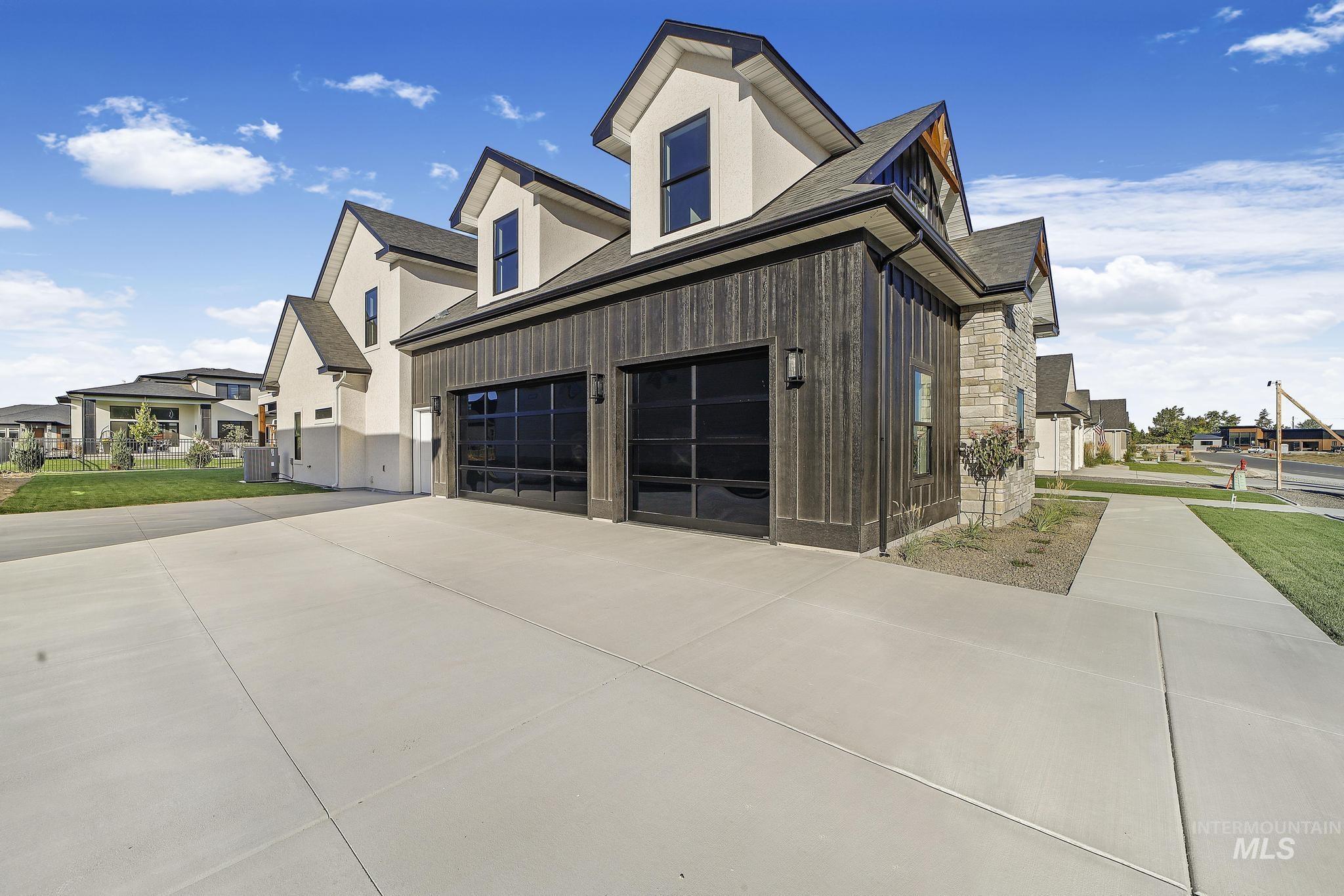 View of side of property featuring stone siding, a shingled roof, driveway, and a residential view
