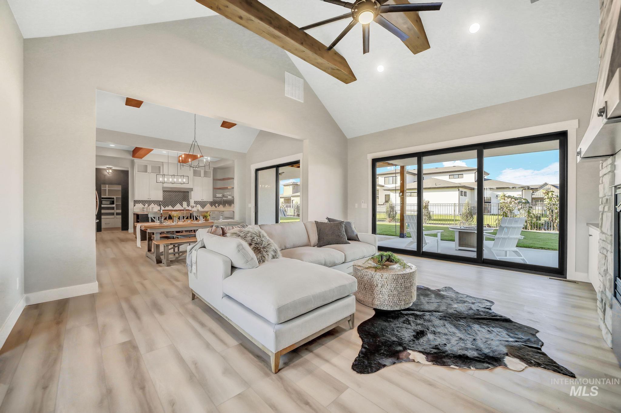 Living area with beam ceiling, healthy amount of natural light, high vaulted ceiling, light wood-style flooring, and recessed lighting
