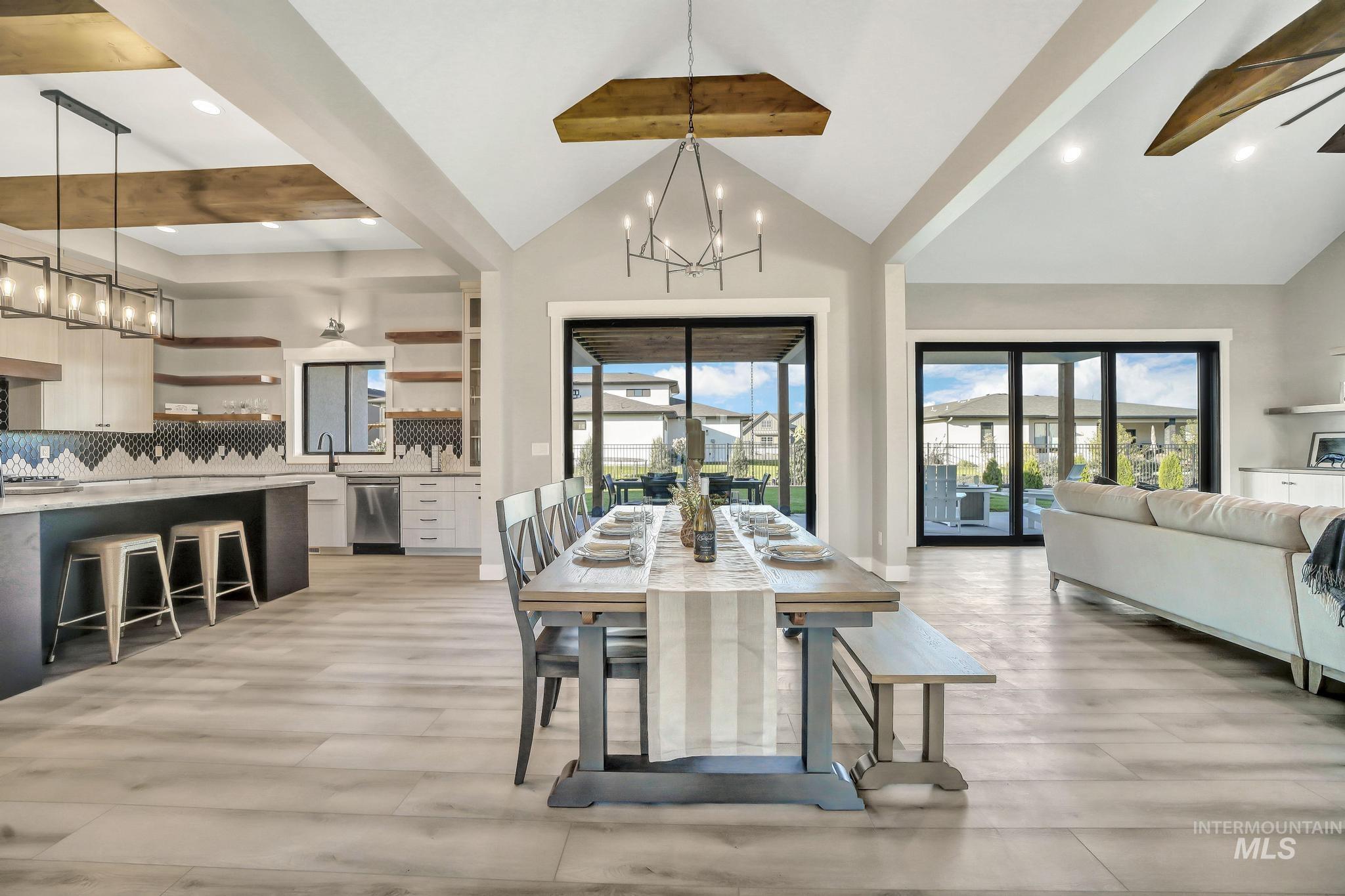 Dining space with a chandelier, beamed ceiling, high vaulted ceiling, light wood finished floors, and ceiling fan