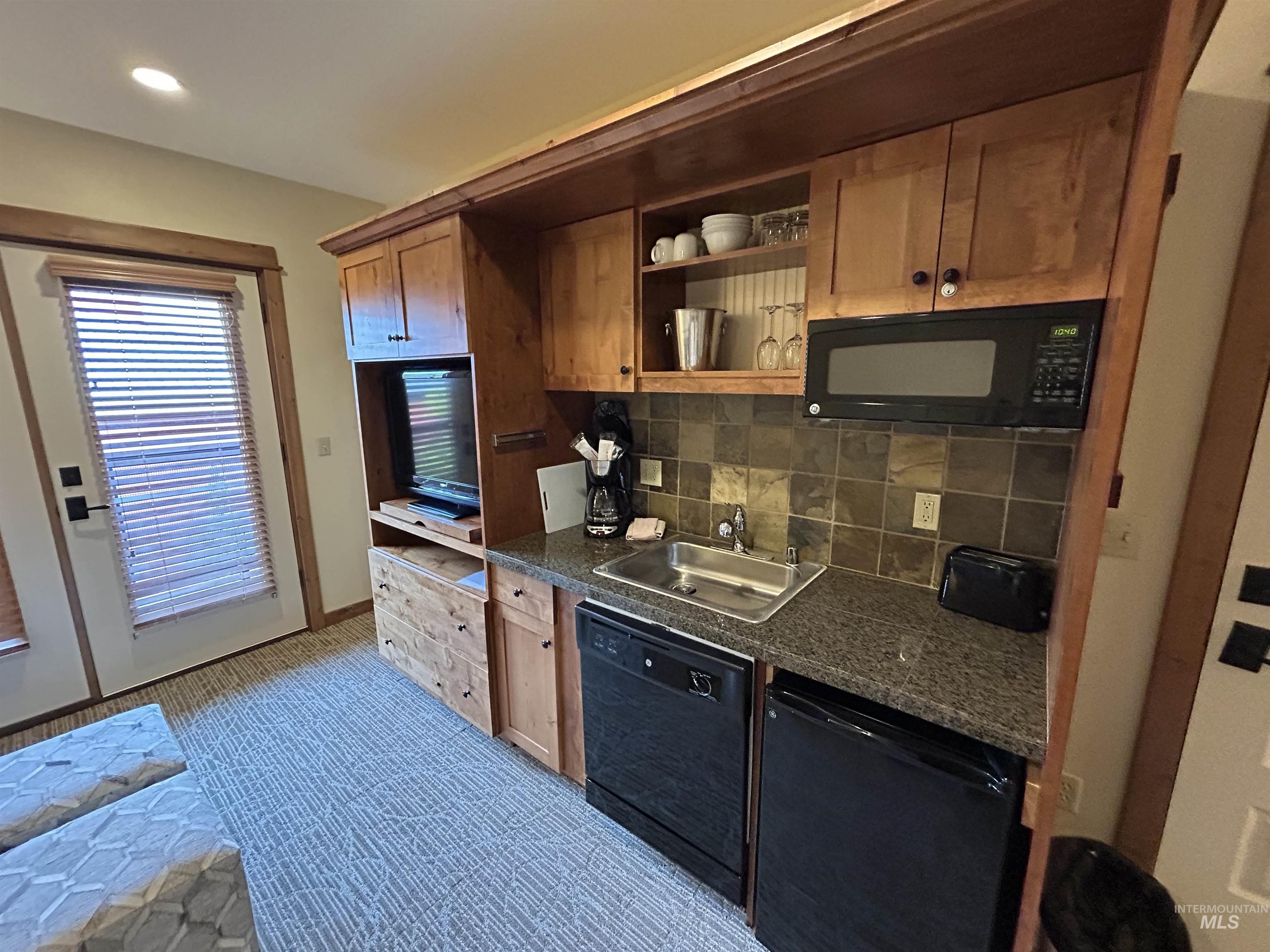 Kitchen with dark countertops, tasteful backsplash, black appliances, recessed lighting, and open shelves