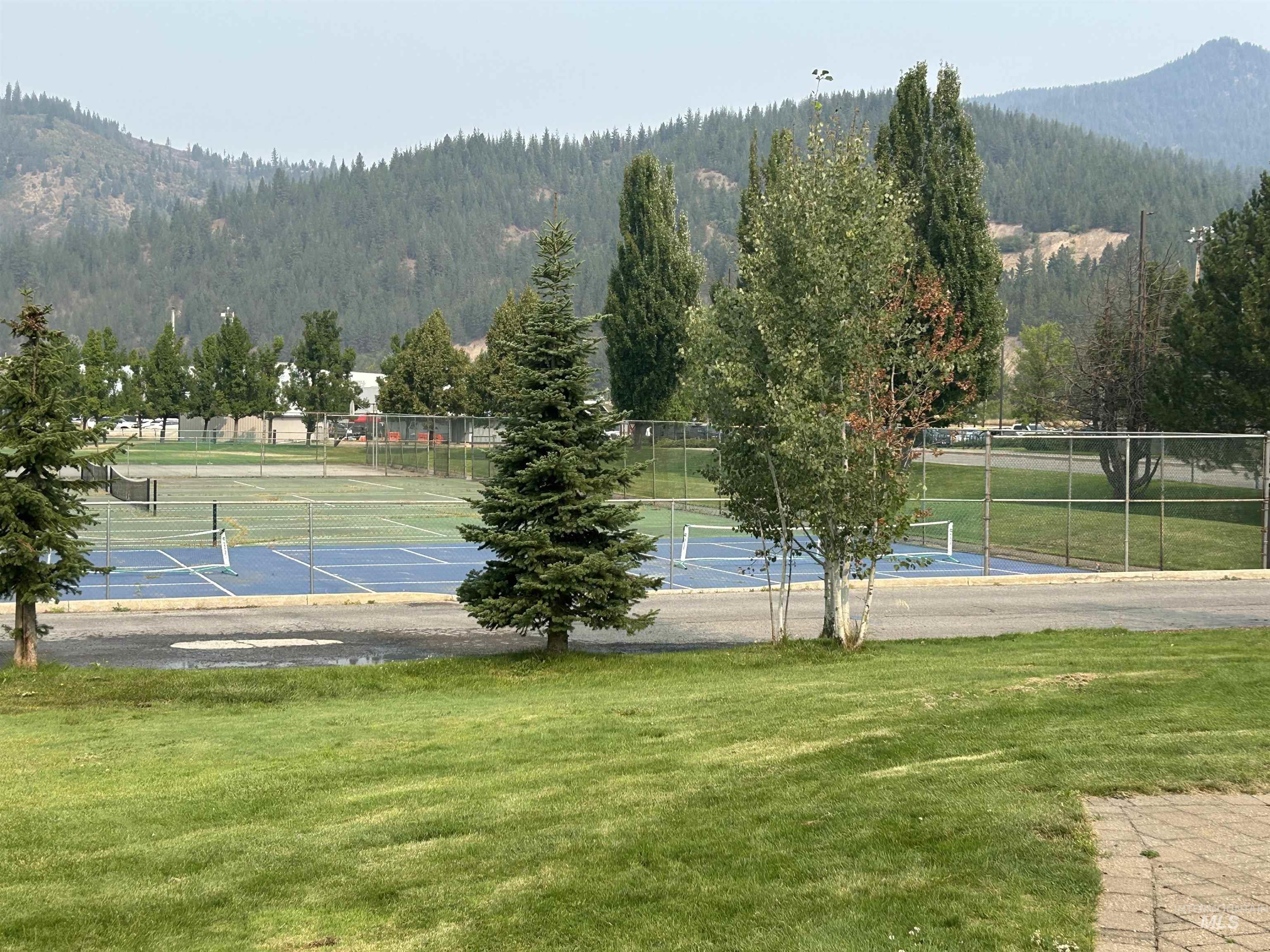 View of tennis court with a forest view and a mountain view