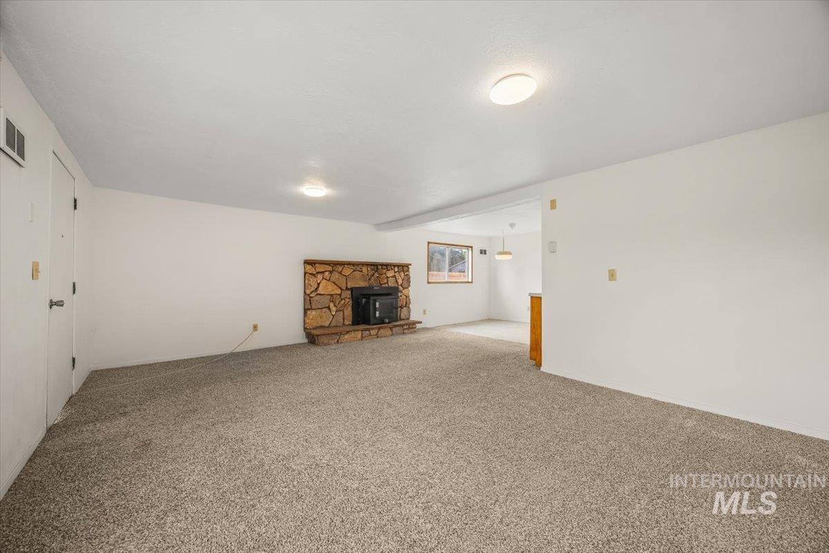 Unfurnished living room featuring a wood stove and carpet floors