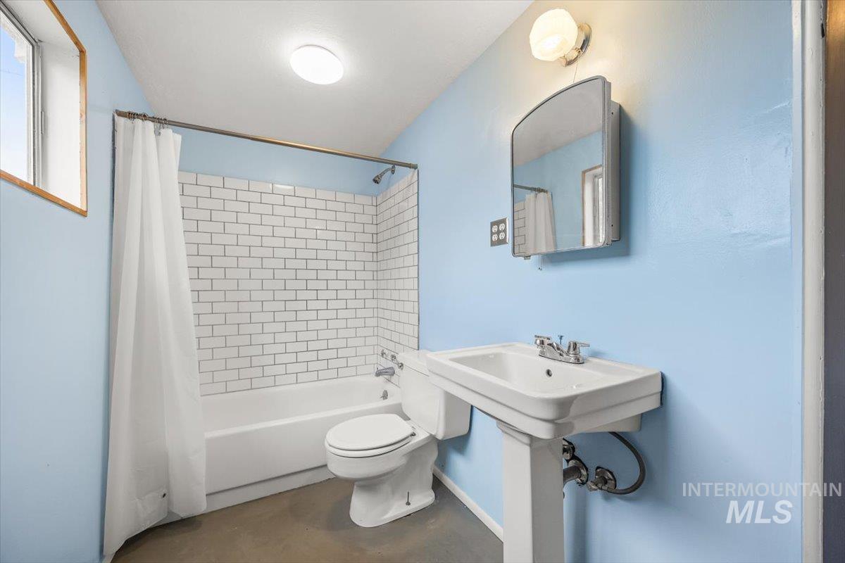 Full bathroom with shower / bath combo and concrete flooring