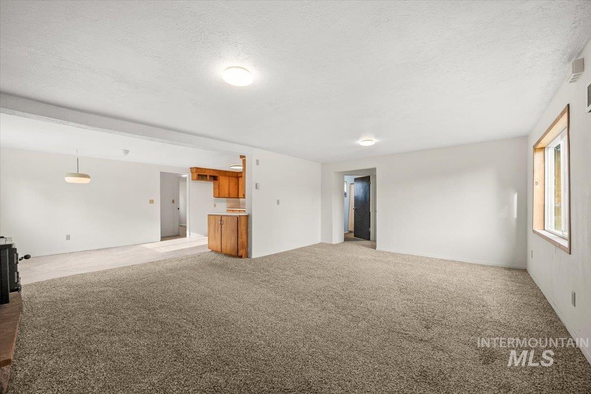 Unfurnished living room with light carpet and a textured ceiling