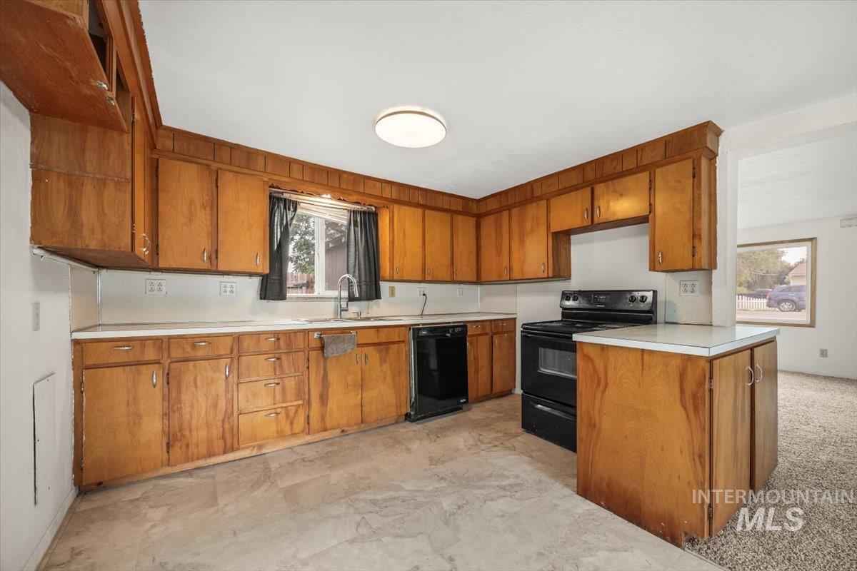 Kitchen with black appliances, light countertops, and brown cabinetry