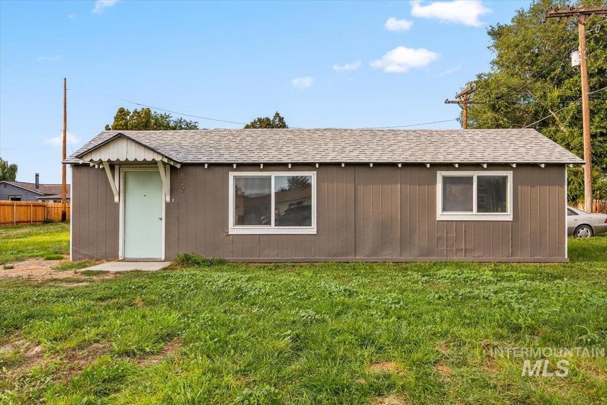 Back of house featuring roof with shingles and a lawn