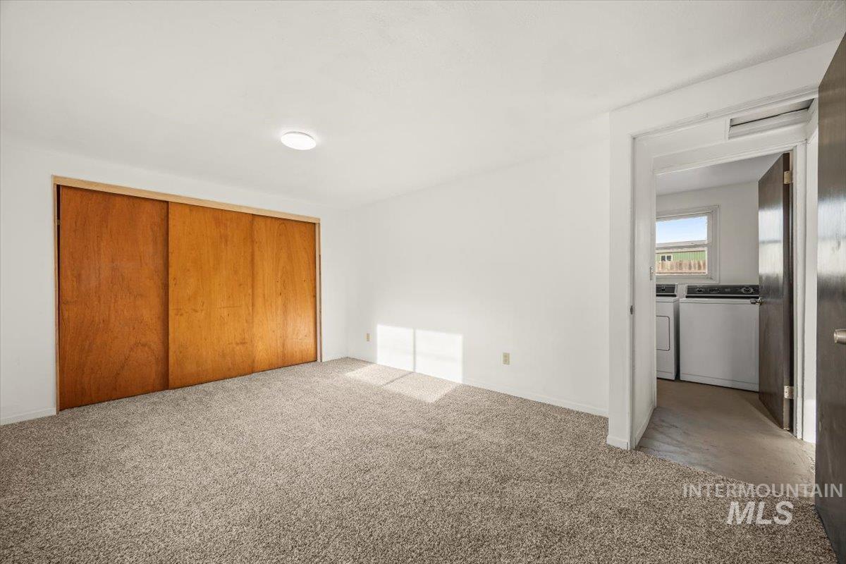 Unfurnished bedroom with washer and dryer, carpet, and a closet