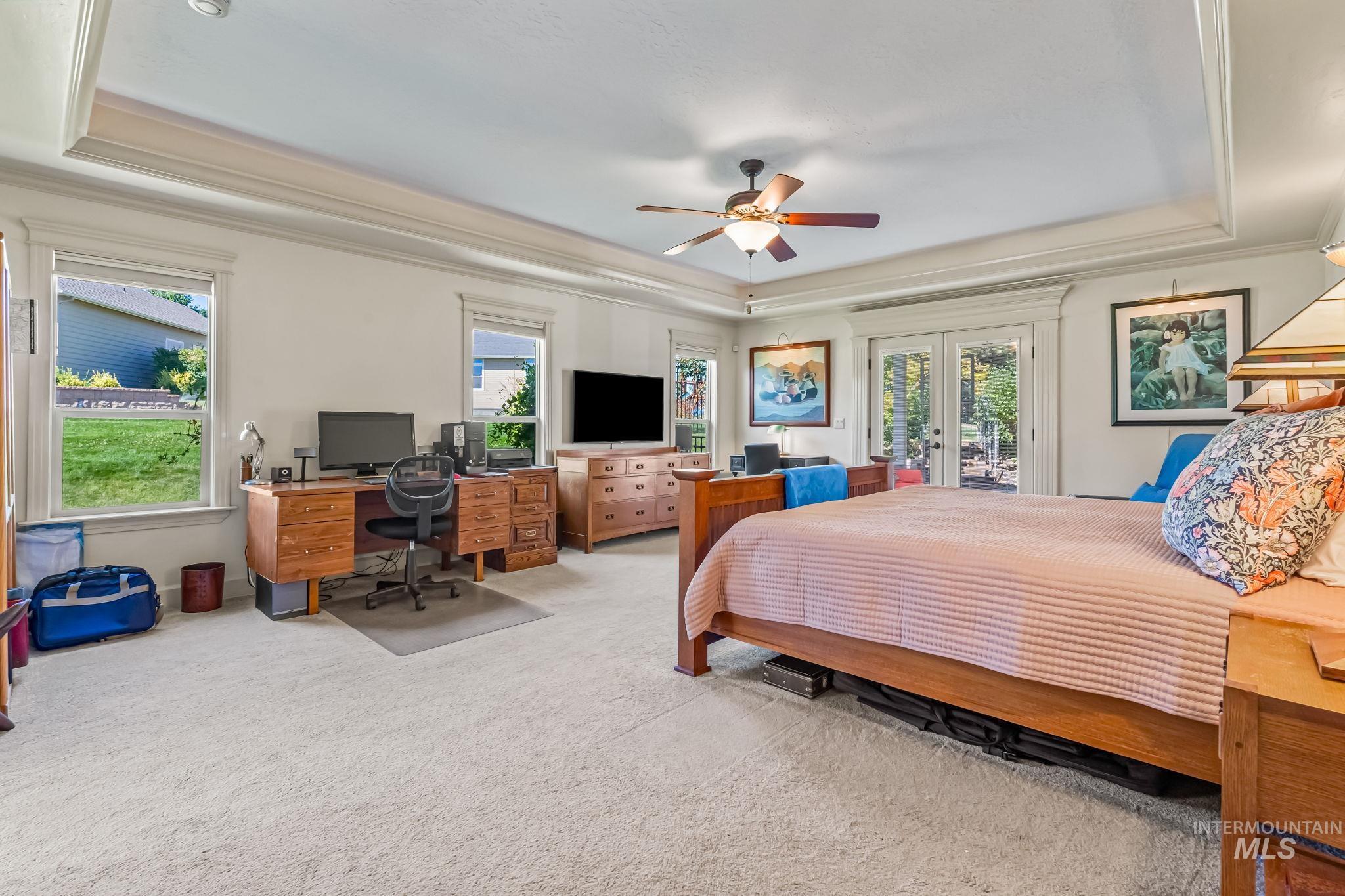 Bedroom with a raised ceiling, french doors, access to exterior, ornamental molding, and an office area