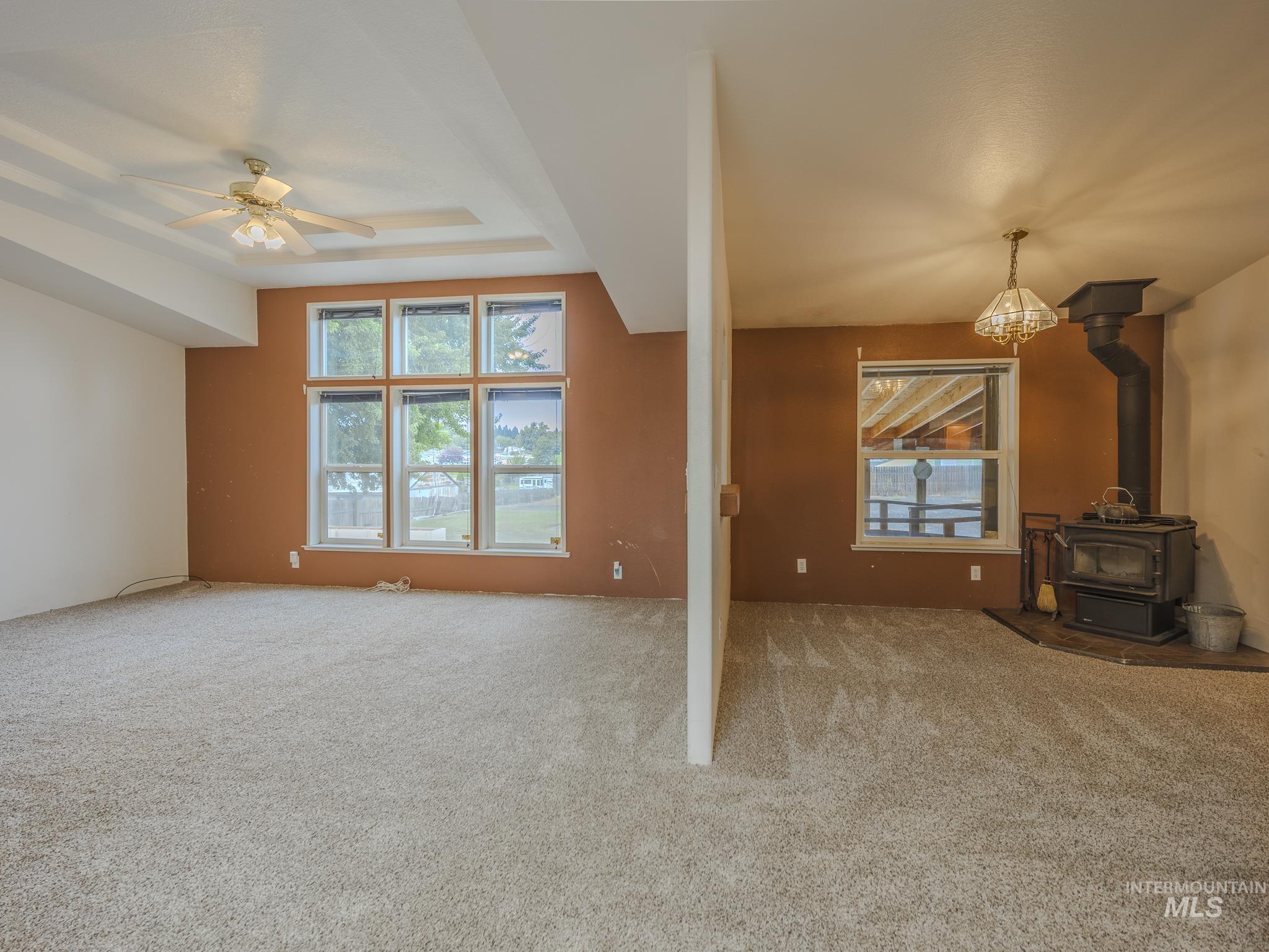 Unfurnished living room with a wood stove, healthy amount of natural light, and carpet flooring