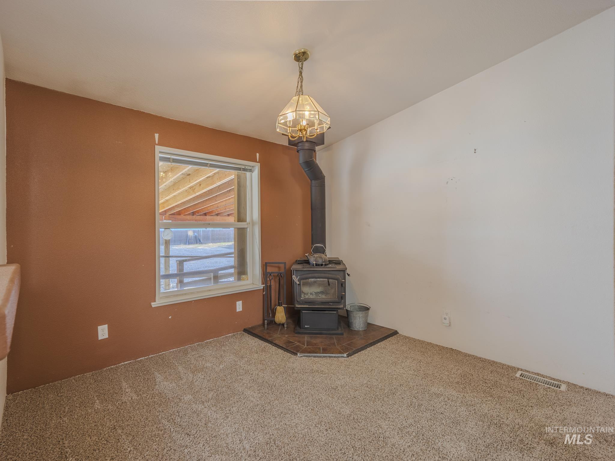 Unfurnished living room with a wood stove and carpet floors