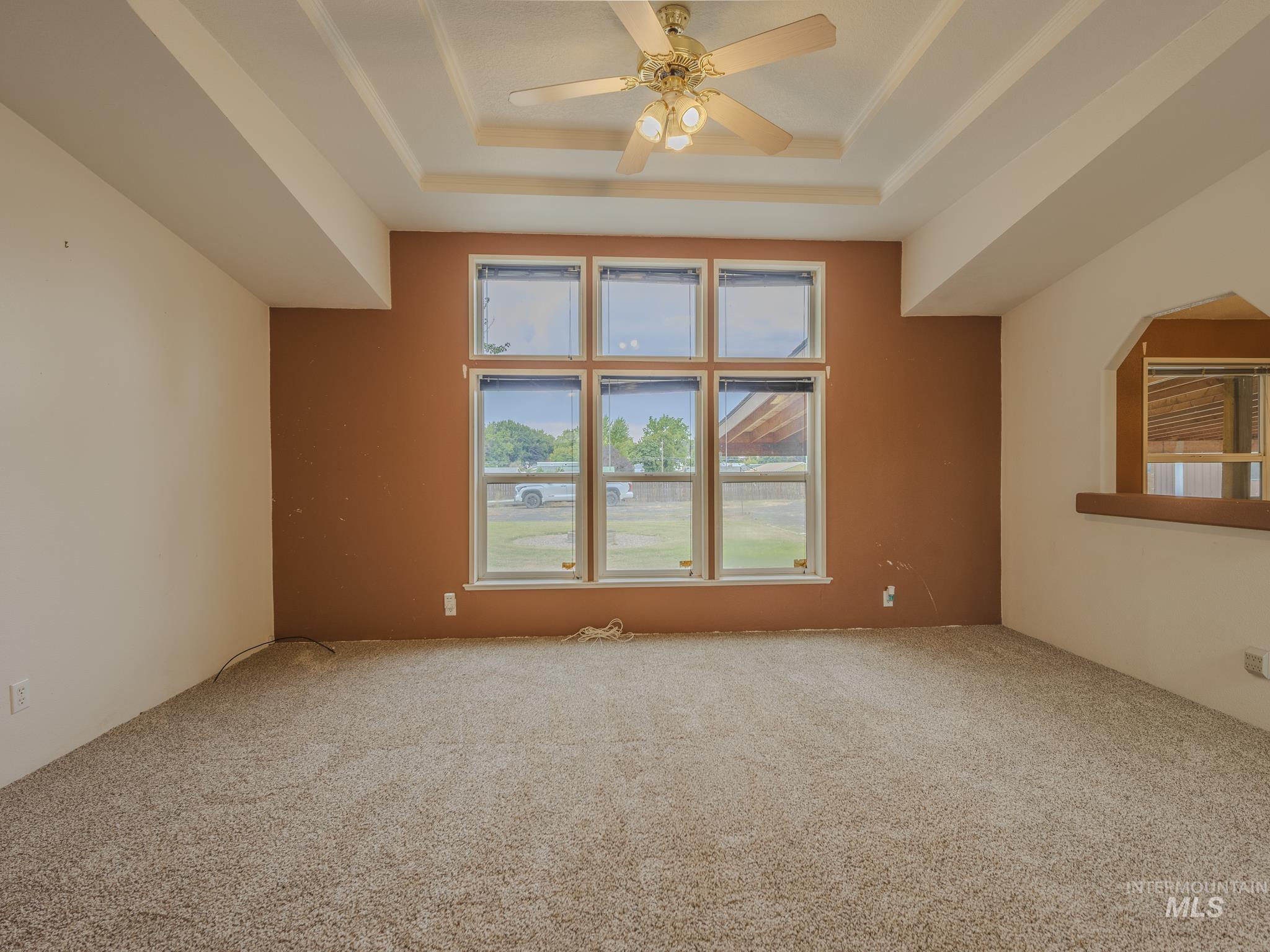 Carpeted spare room with a tray ceiling and ceiling fan