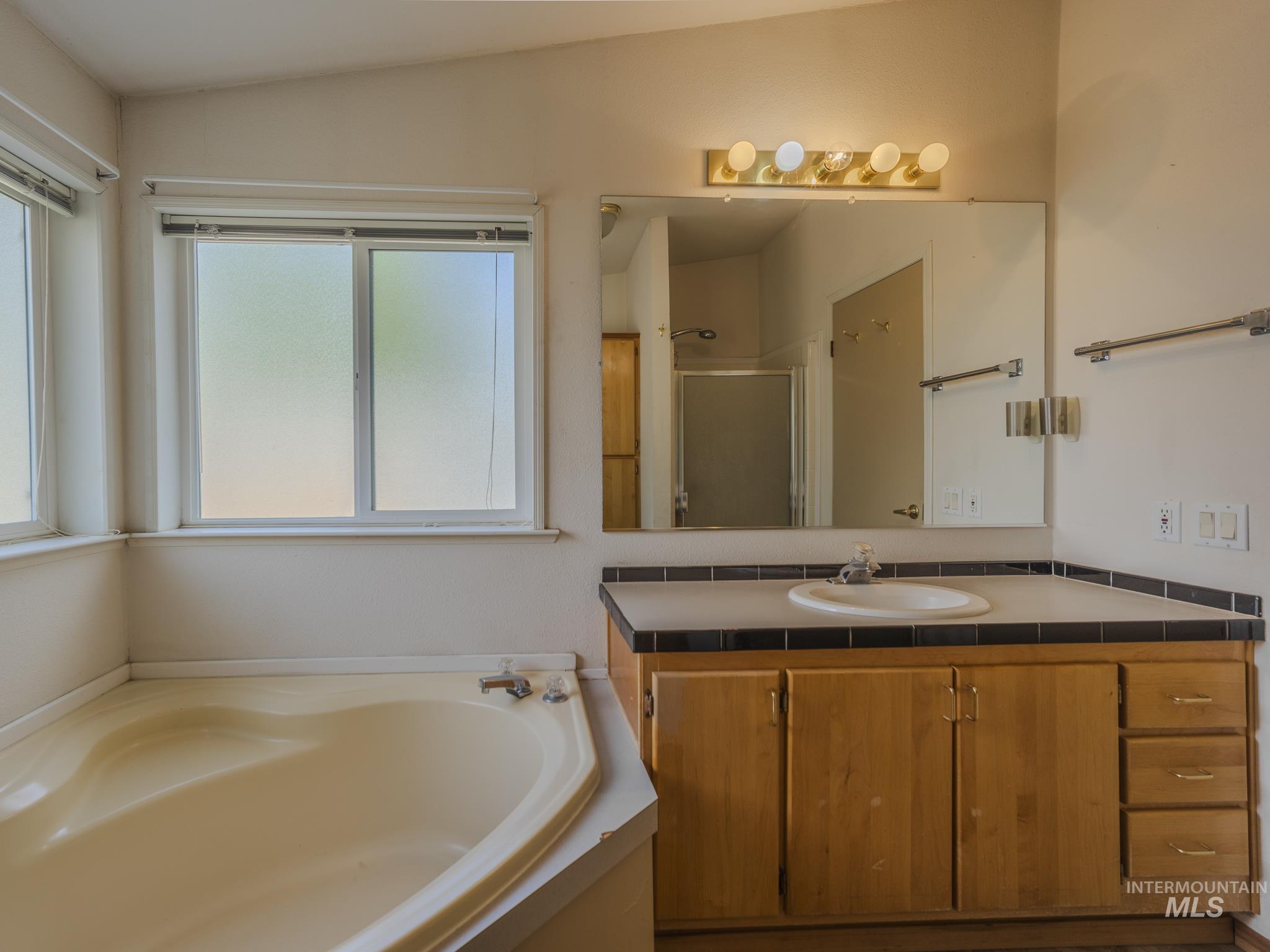 Bathroom with a shower stall, vanity, and a garden tub