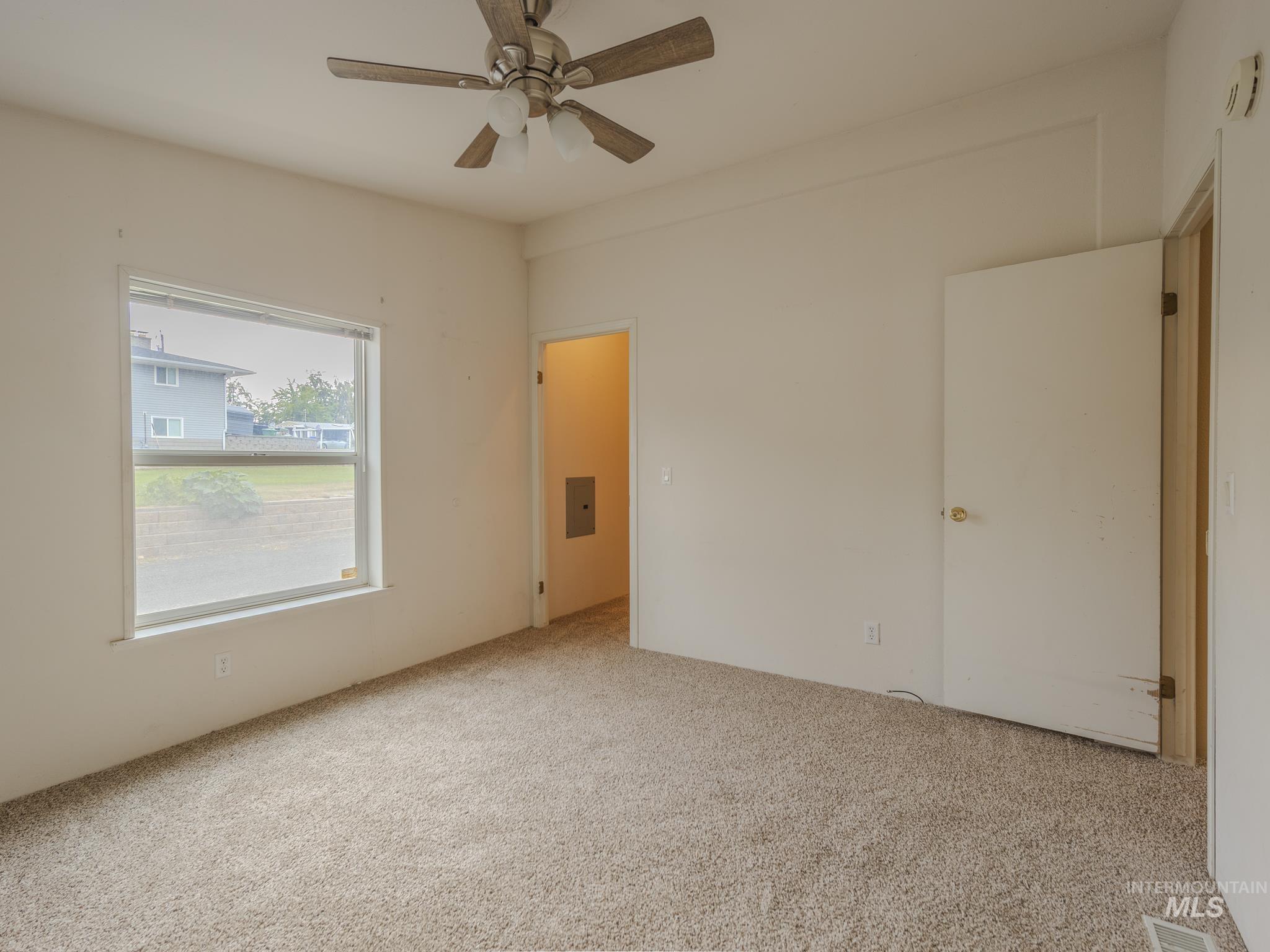 Empty room with carpet floors, a ceiling fan, and electric panel