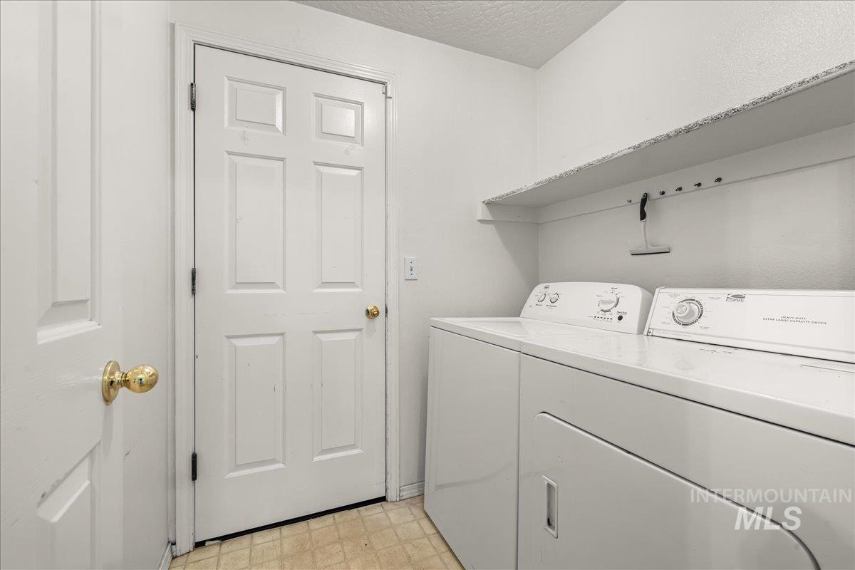 Laundry room with a textured ceiling, washer and clothes dryer, and light floors