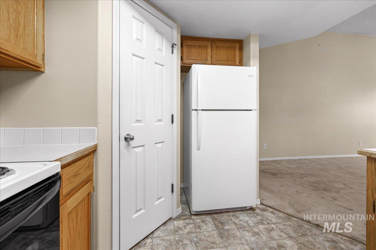 Kitchen with white appliances, brown cabinetry, and tile countertops