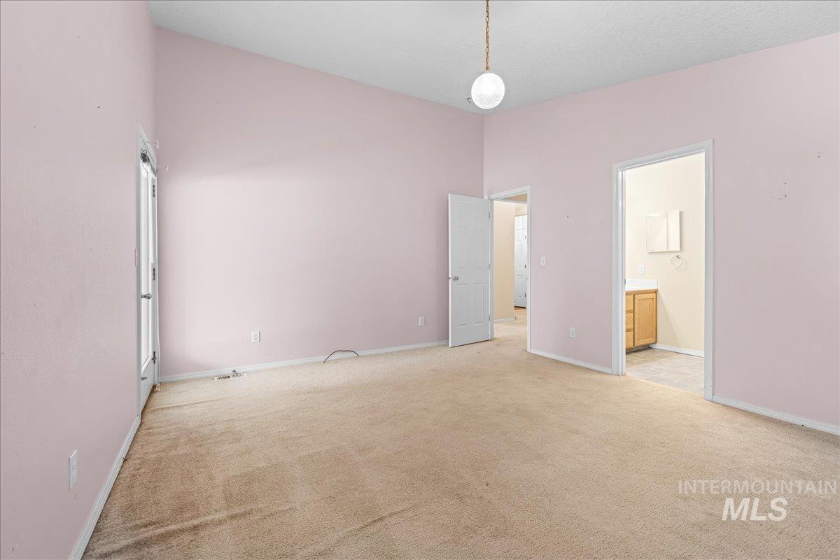 Unfurnished bedroom with light colored carpet and connected bathroom