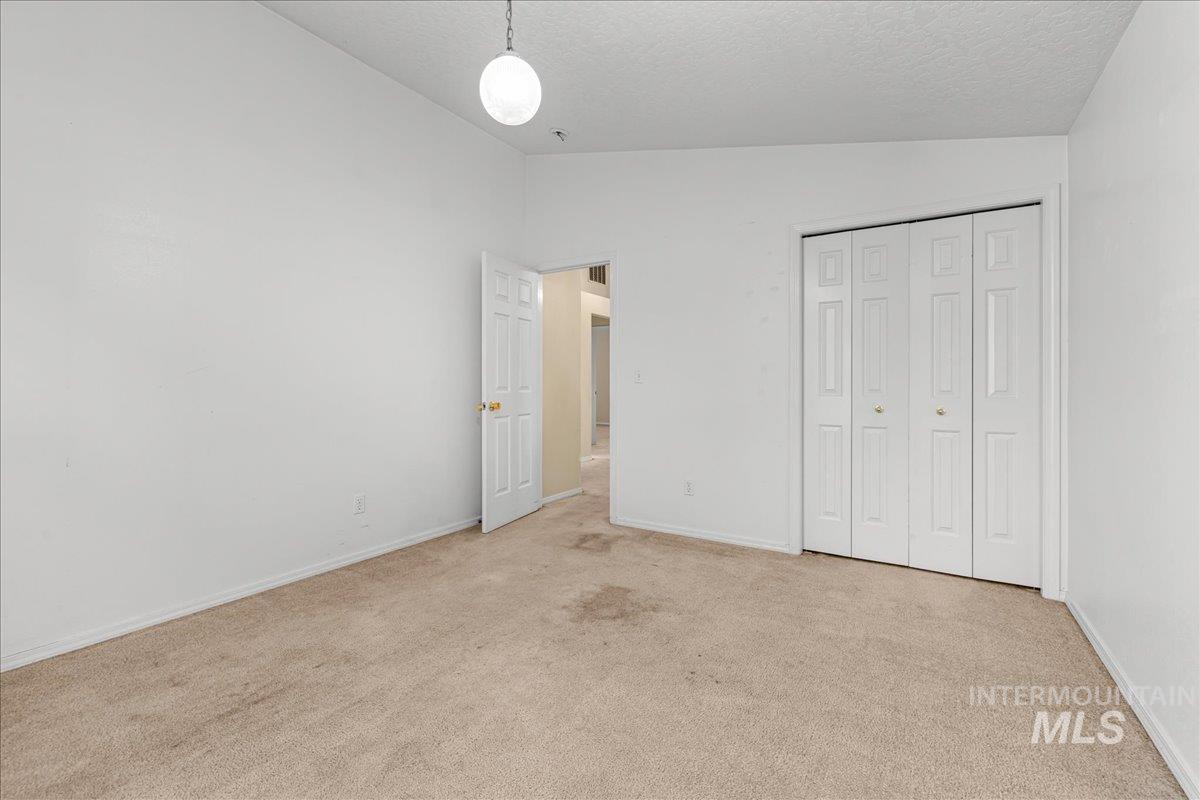 Unfurnished bedroom featuring vaulted ceiling, carpet flooring, a closet, and a textured ceiling