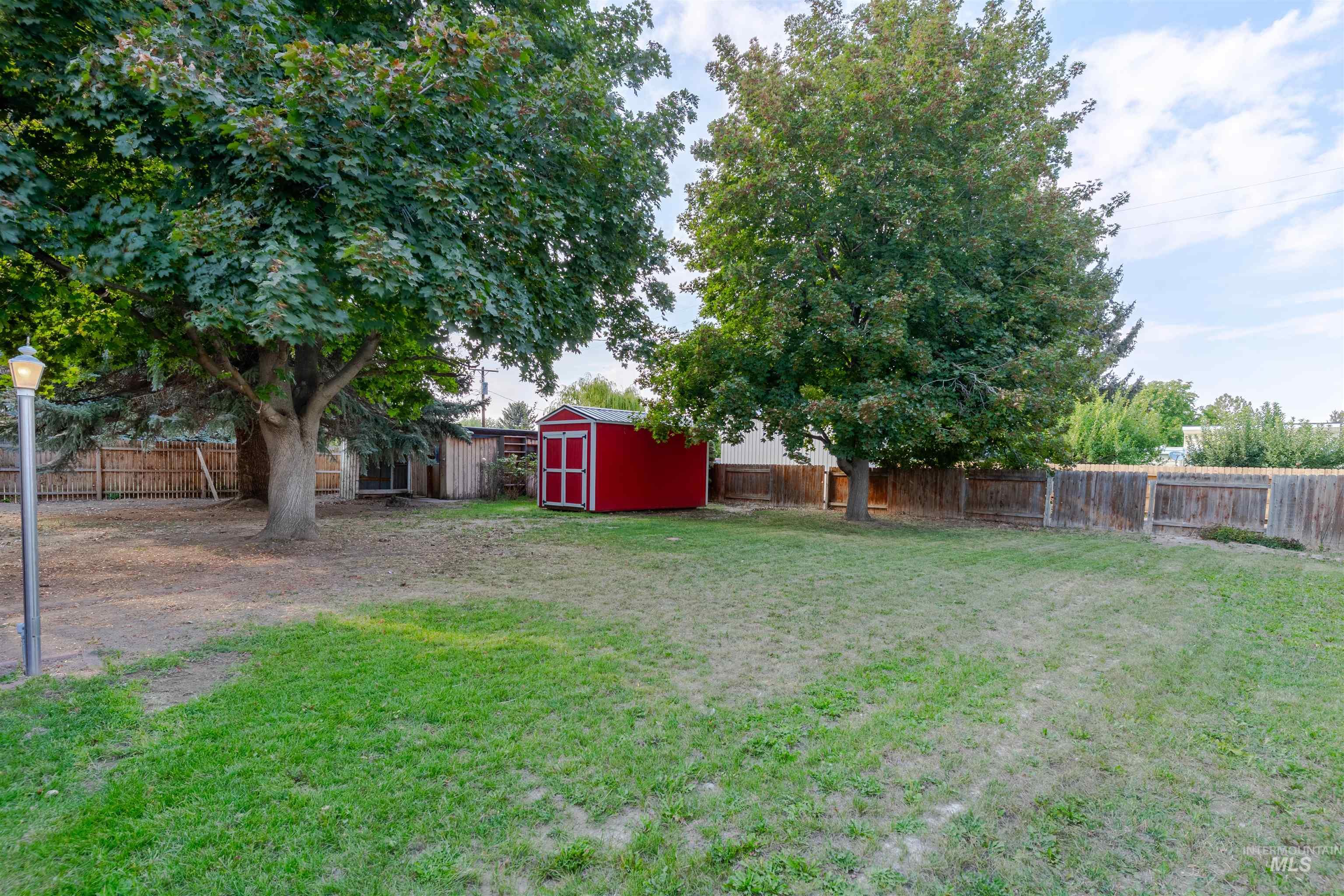 Fenced backyard featuring a storage unit