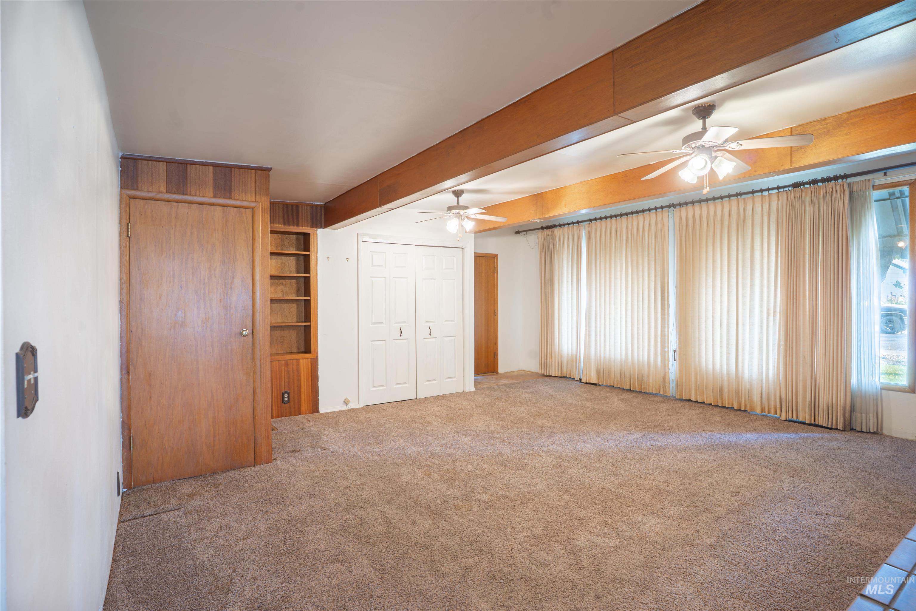 Unfurnished bedroom with carpet floors, beamed ceiling, a closet, and a ceiling fan