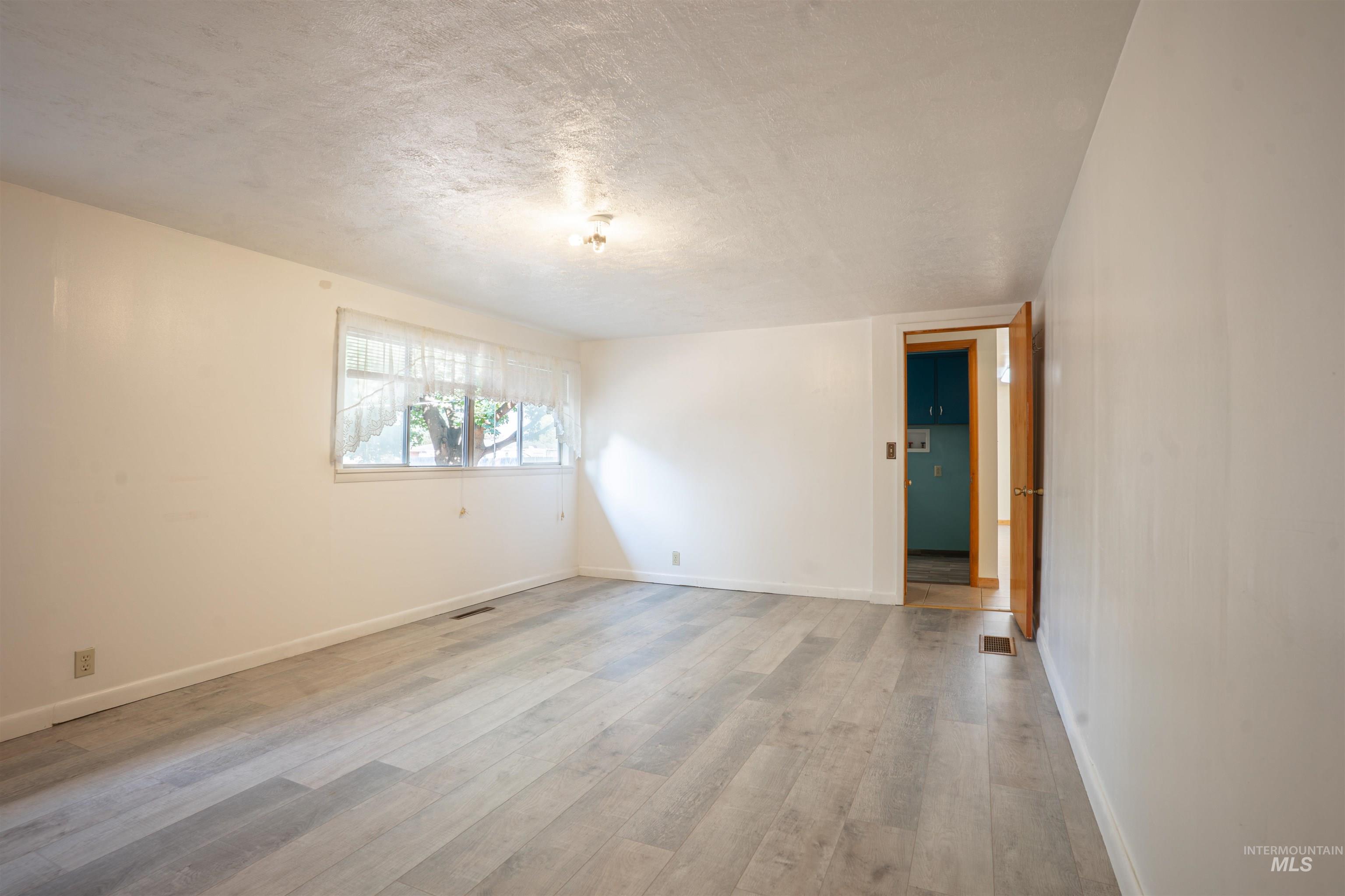 Empty room with a textured ceiling and light wood-style floors