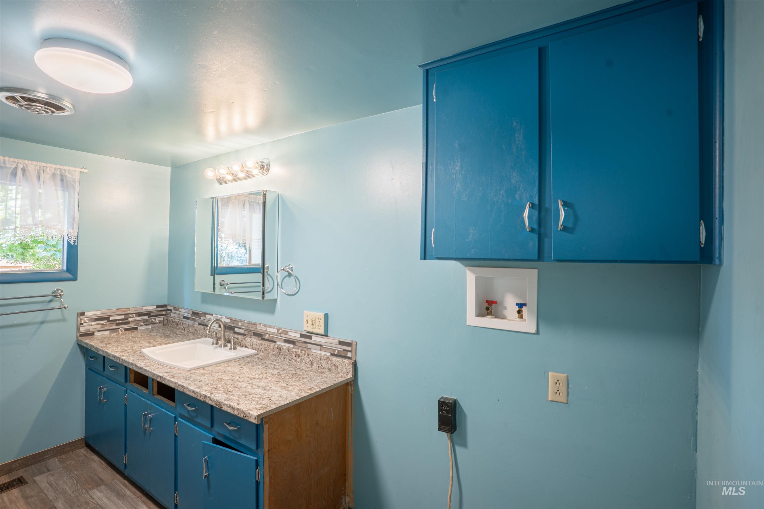 Bathroom featuring tasteful backsplash, vanity, wood finished floors, and healthy amount of natural light