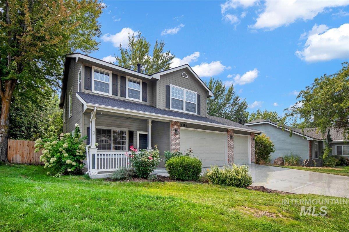 Traditional home with brick siding, a porch, concrete driveway, and a front lawn