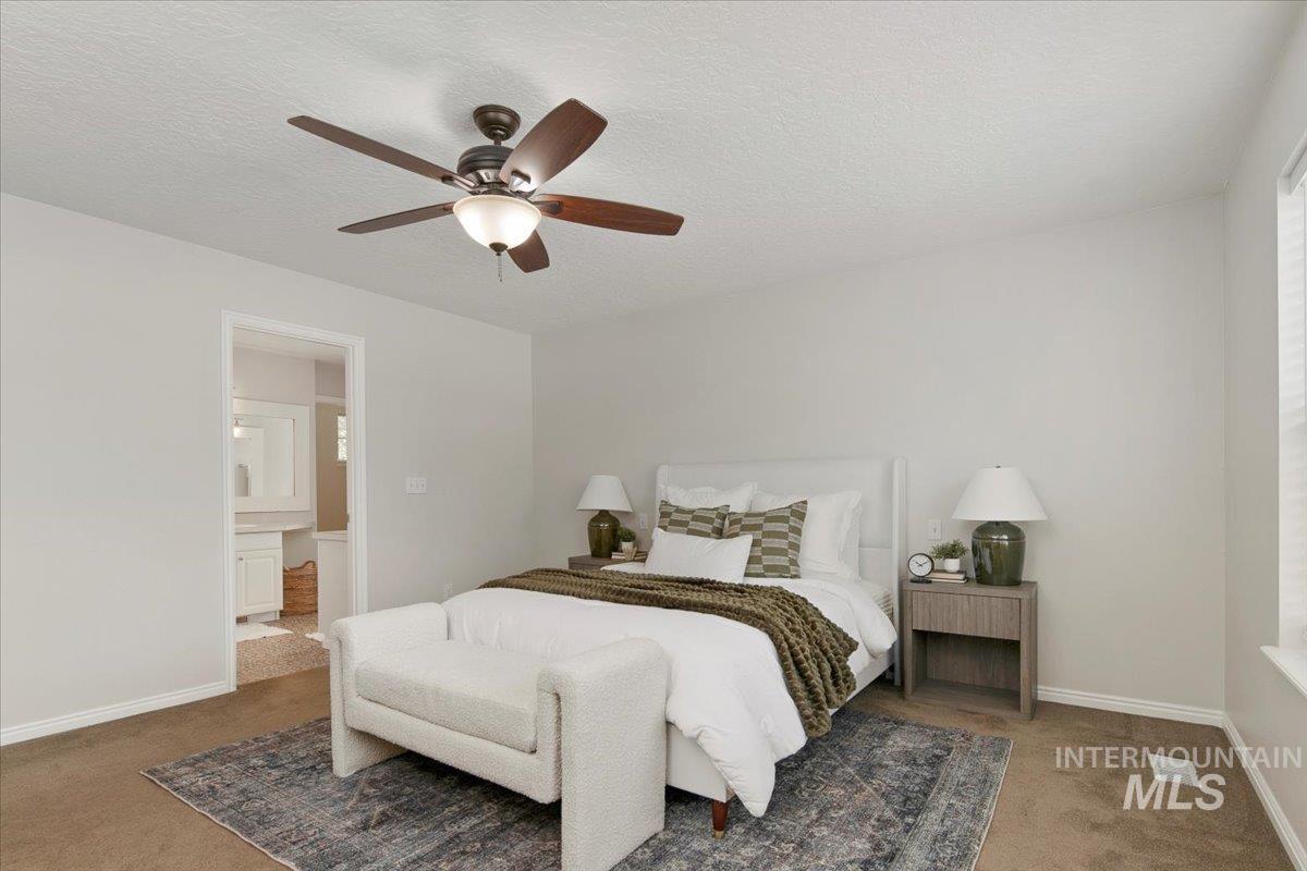 Carpeted bedroom with a textured ceiling, ensuite bathroom, and a ceiling fan