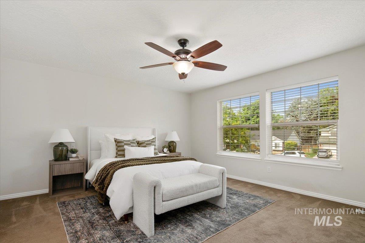 Carpeted bedroom with a textured ceiling and ceiling fan
