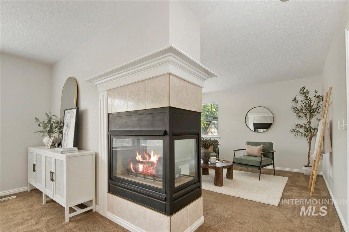 Living room featuring light carpet, a fireplace, and a textured ceiling